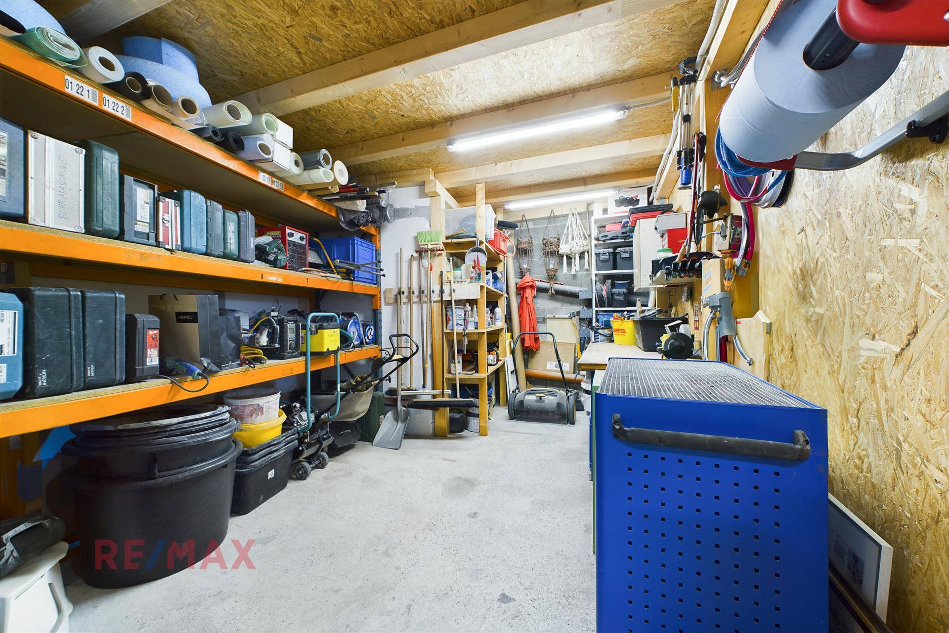 Werkstatt oder Lagerraum mit Regalen, Werkzeugen und Holzverkleidung.