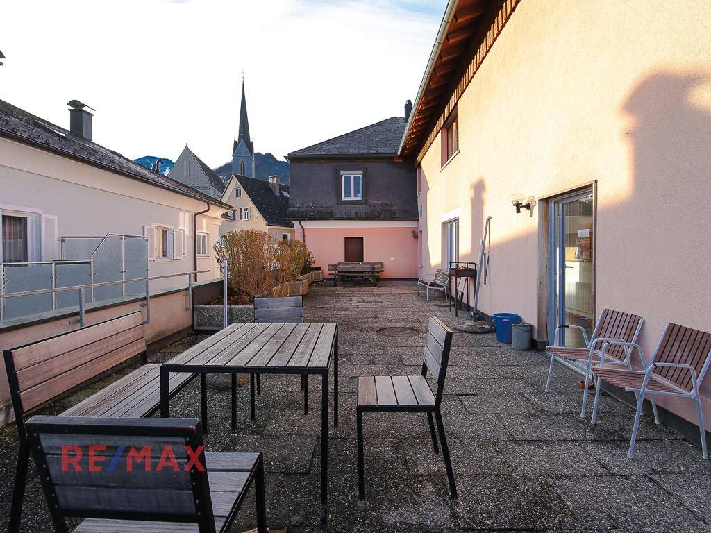 Geräumige Terrasse mit Holztischen und Stühlen, ideal für Mahlzeiten im Freien.