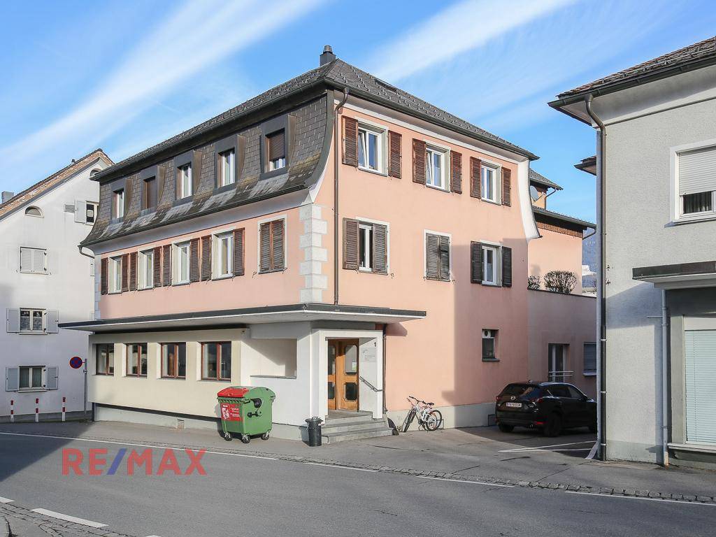 Ansicht des Mehrfamilienhauses von der Straße mit Mansarddach und Fensterläden.