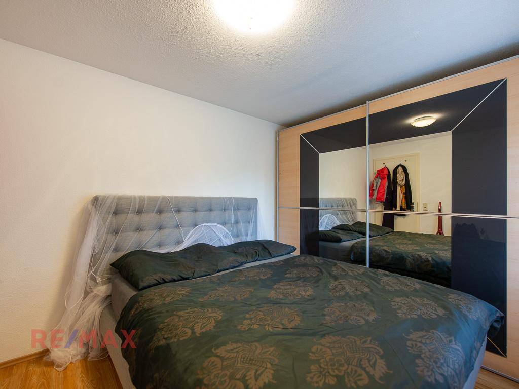 Helles Schlafzimmer mit Doppelbett, Holzboden und großem Spiegelschrank.