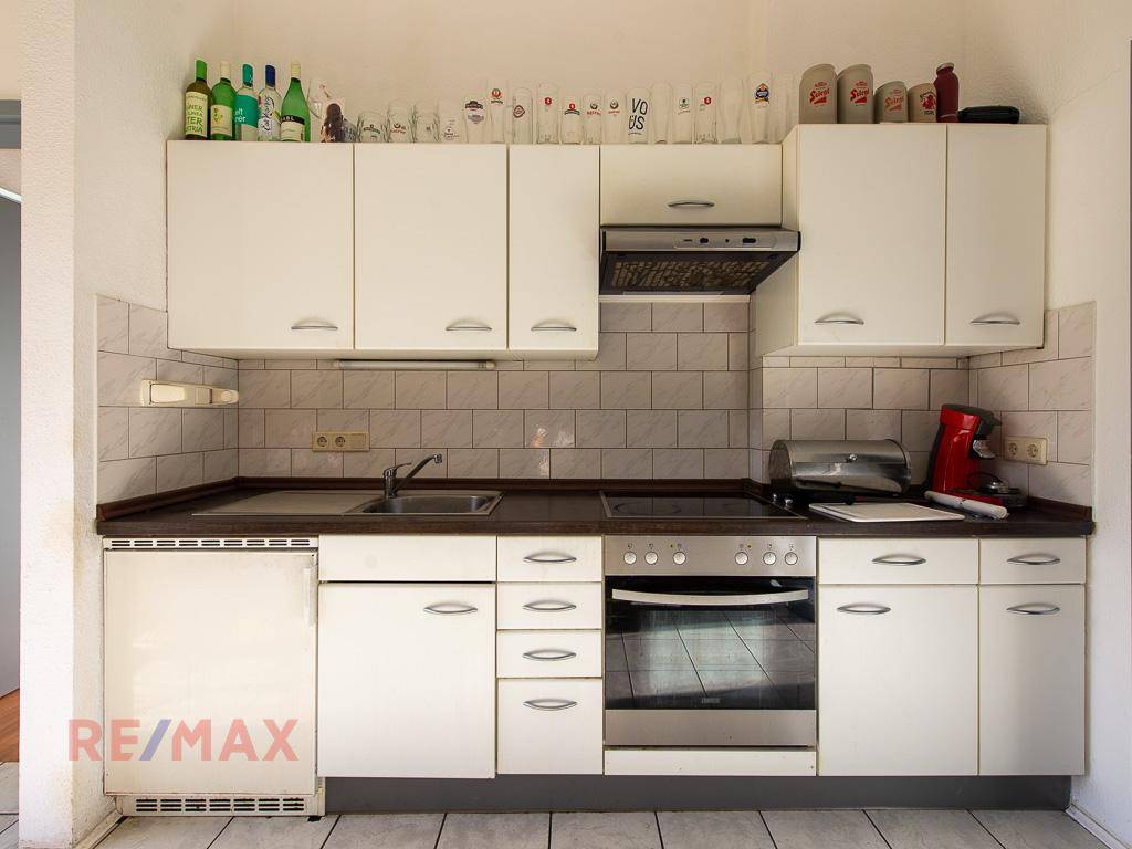 Moderne Küche mit weißen Schränken, Herd und dunkler Arbeitsplatte.