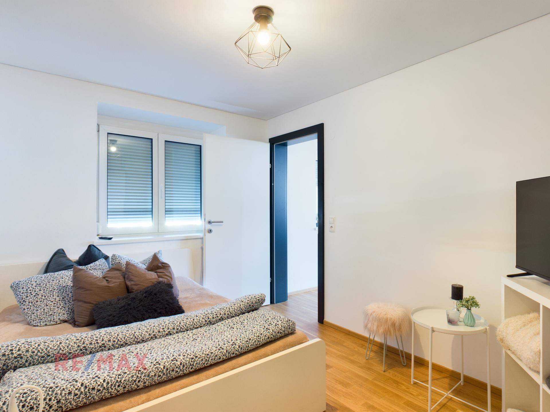 Helles Schlafzimmer mit Holzboden, Doppelbett und minimalistischer Einrichtung.