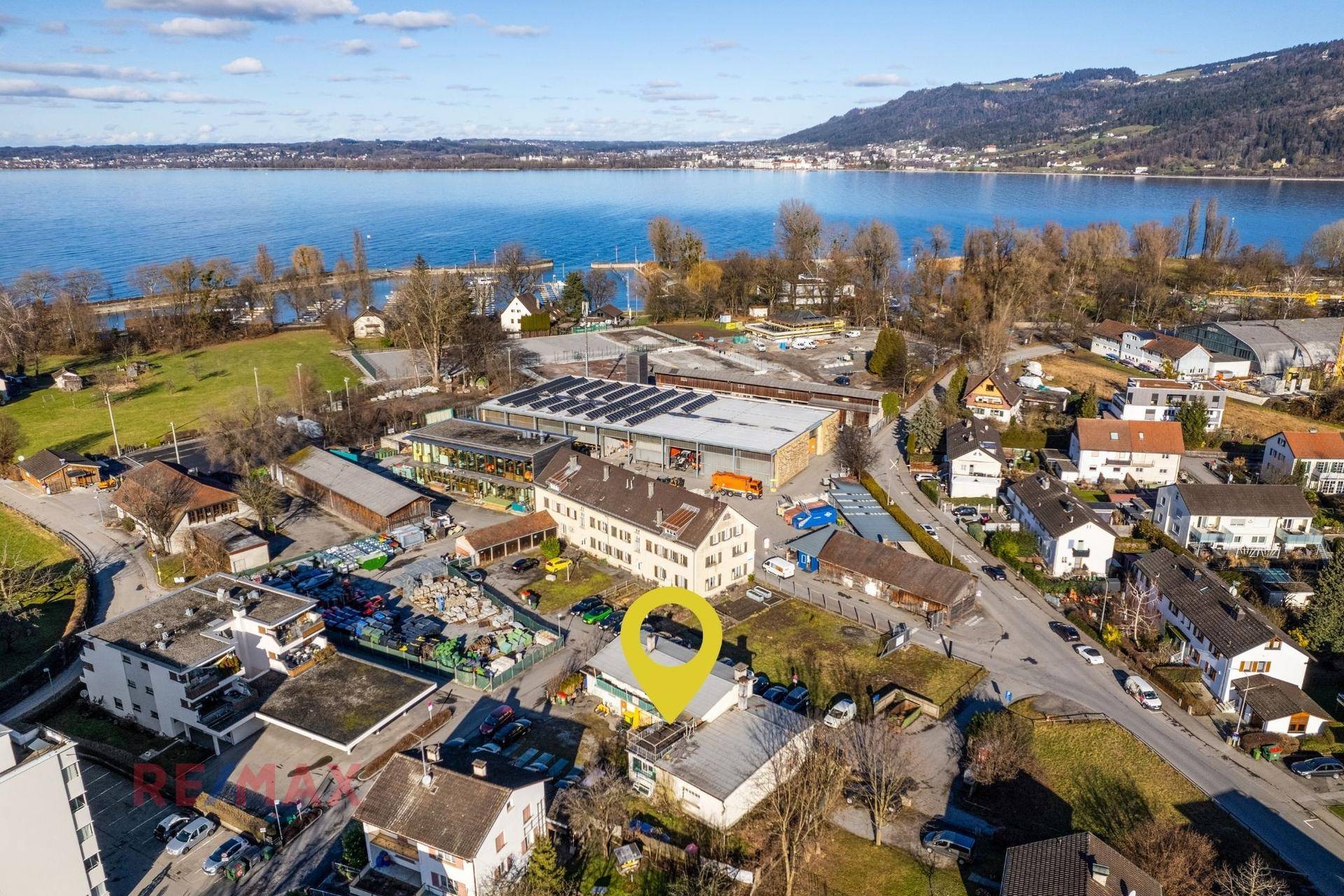 Weitläufige Luftaufnahme der Immobilie mit Blick auf den See, die Berge und die umliegende Stadt.