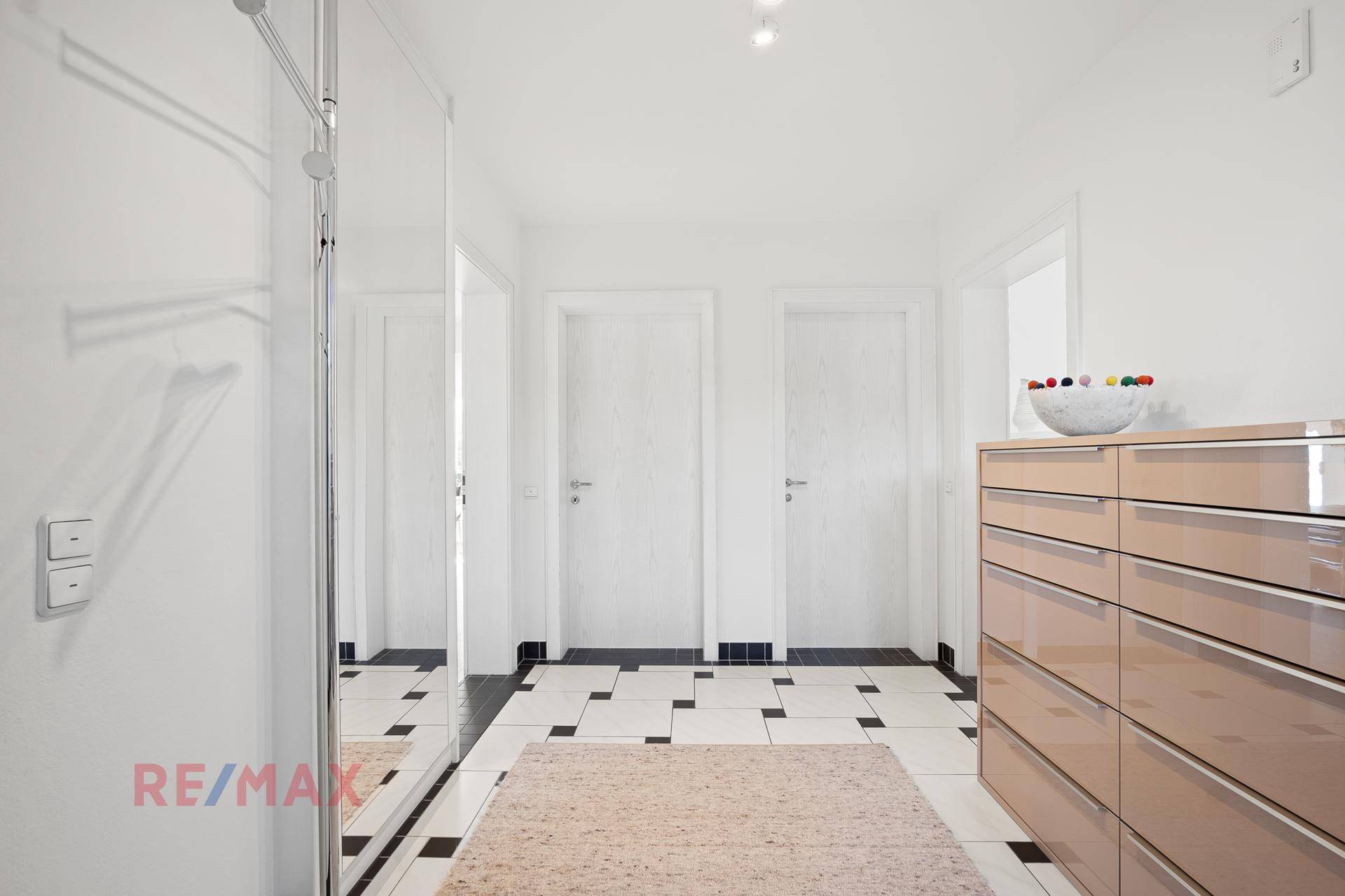 Heller Eingangsbereich mit Fliesenboden, Spiegelschrank und moderner Kommode.
