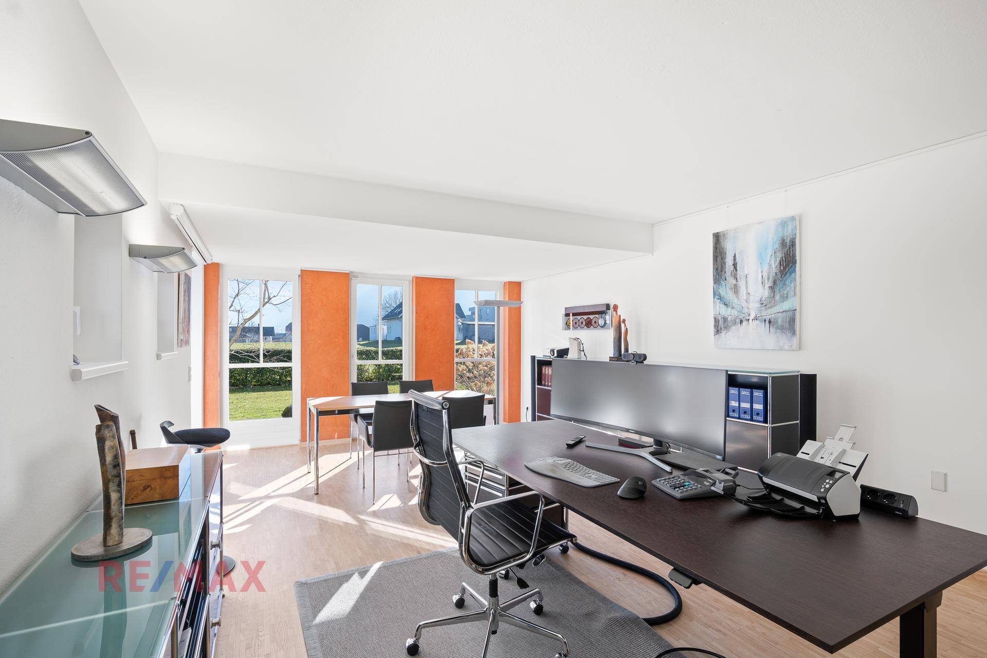 Geräumiges Büro mit hellem Boden, großen Fenstern und Blick ins Grüne.