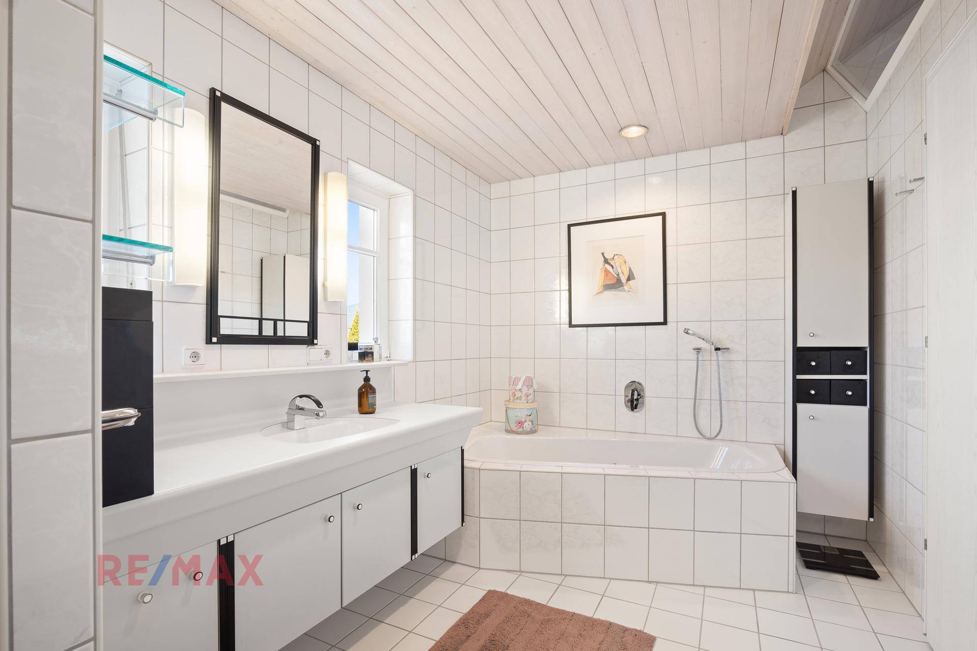 Modernes Badezimmer mit Badewanne, Einzelwaschbecken und weißem Fliesenboden.