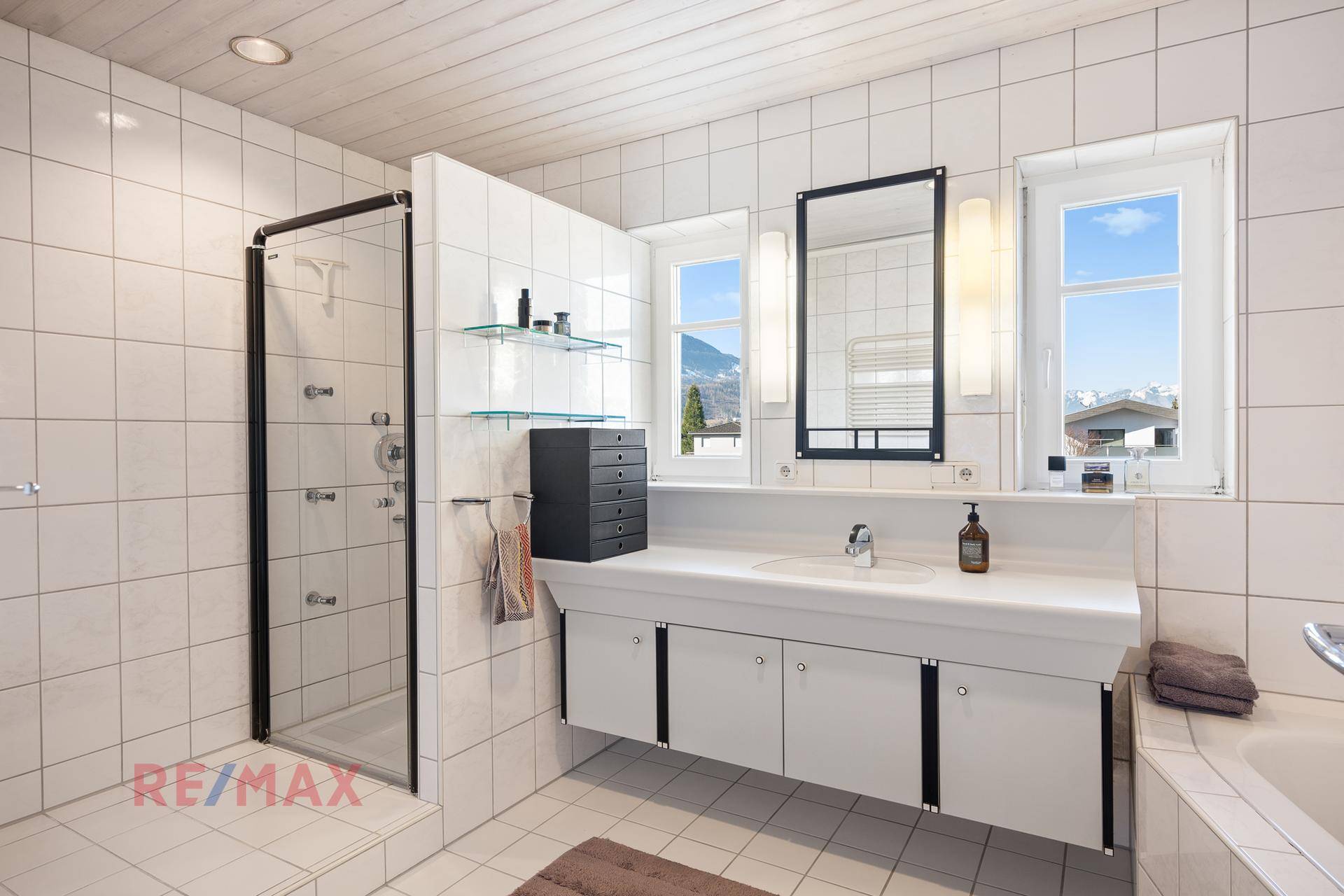 Helles Badezimmer mit Dusche, Einzelwaschbecken, Badewanne und Fliesenboden.