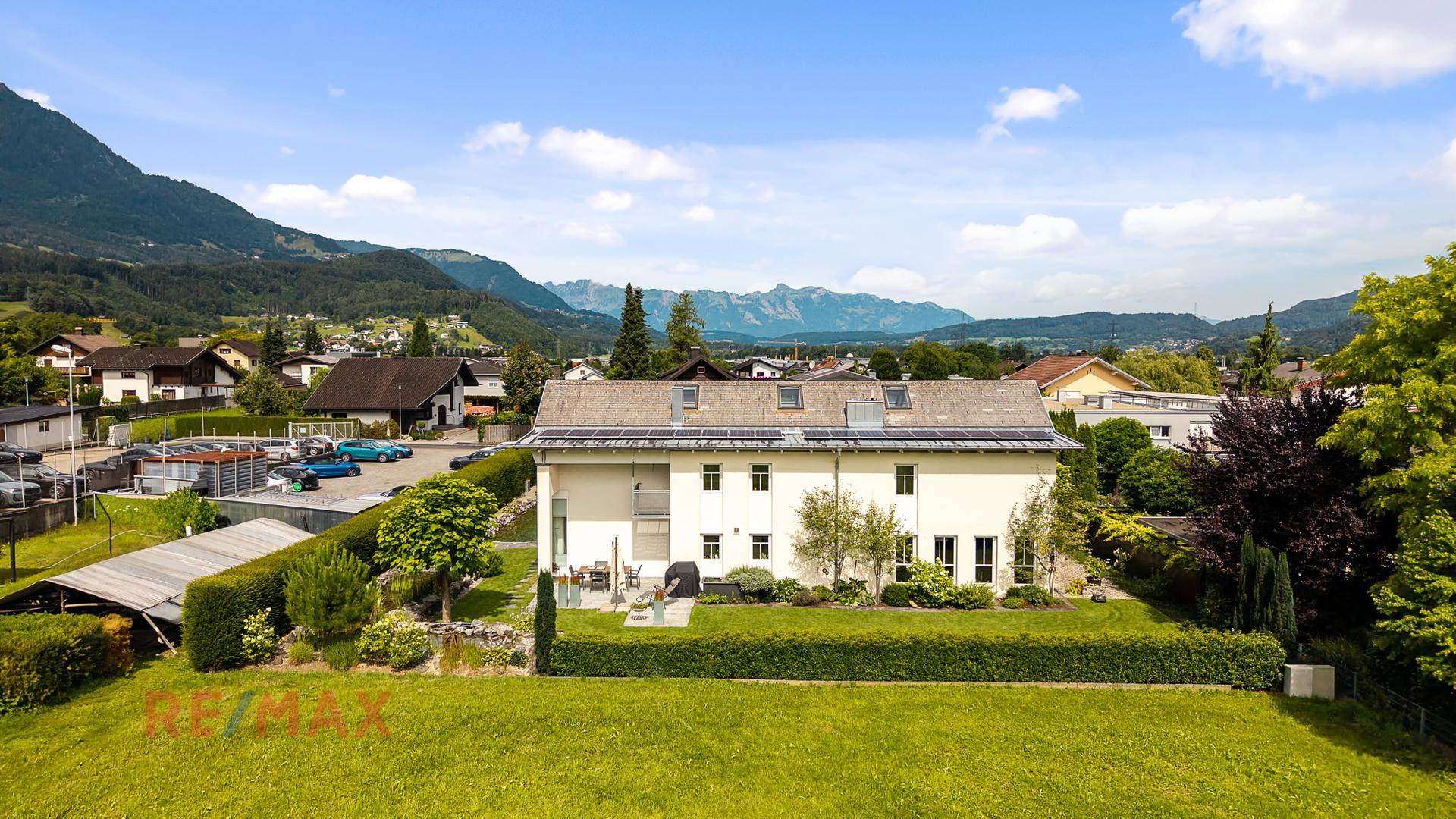 Weitläufige Außenansicht des Hauses mit Garten, Photovoltaikanlage und Bergblick.