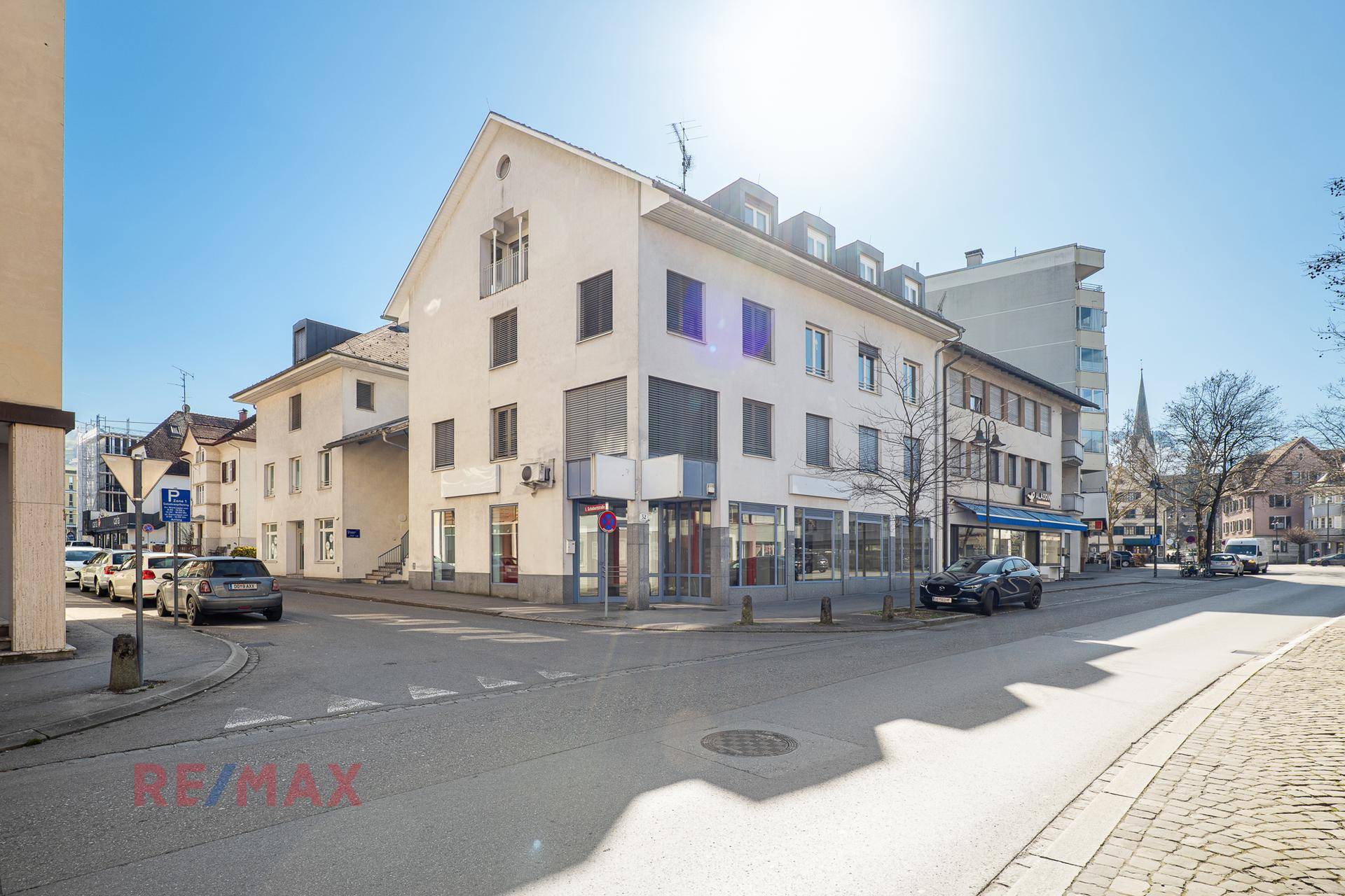 Gebäudeansicht von der Straße mit Geschäften im Erdgeschoss und Wohnungen darüber.