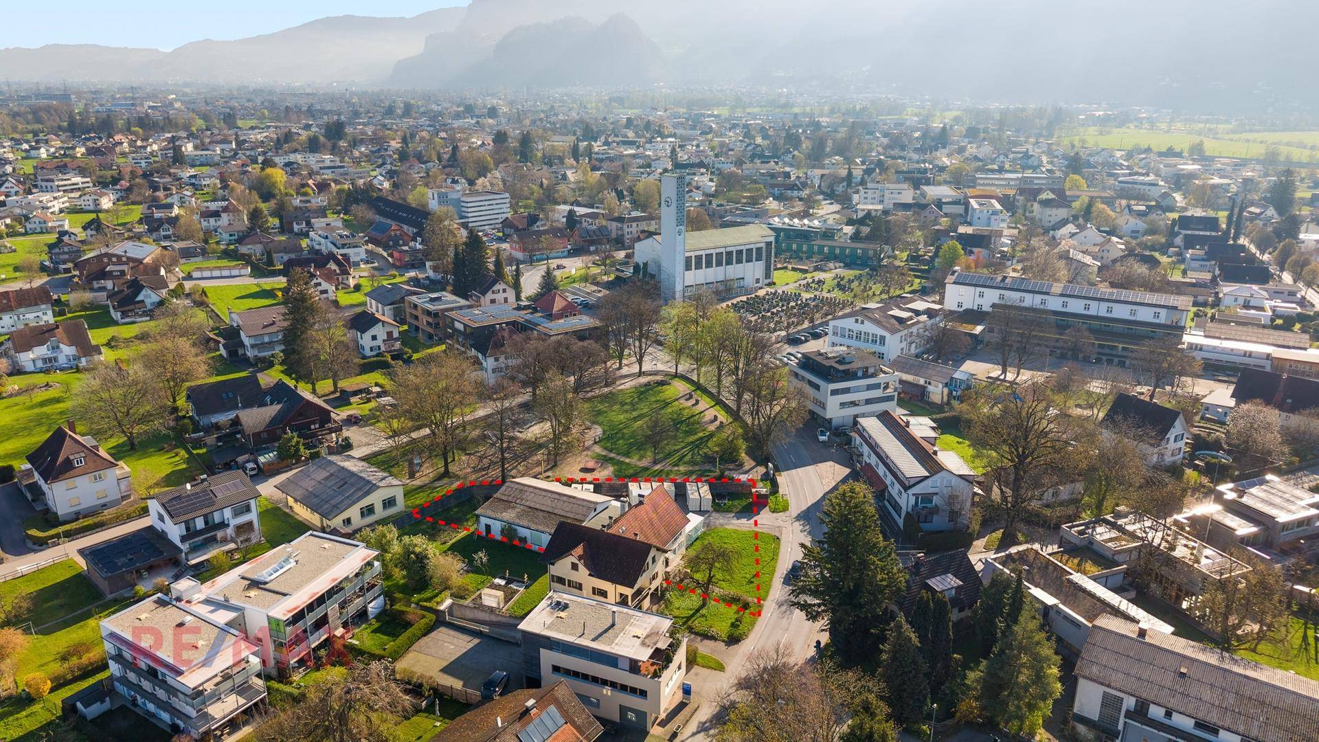 Panoramische Luftaufnahme des Anwesens in einer Gemeinde mit Kirche und Bergkulisse.