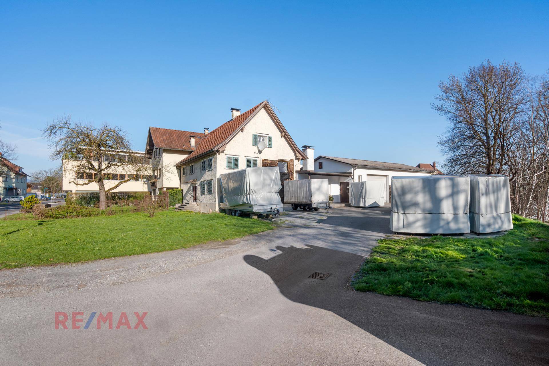 Außenansicht des Anwesens mit Wohnhaus, Nebengebäude und großem gepflasterten Hofbereich.