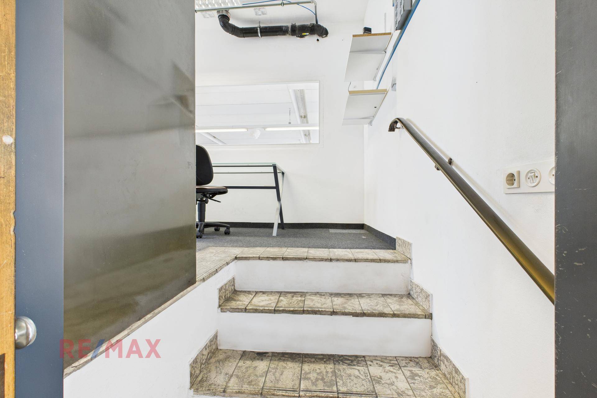 Treppenaufgang zu einem Bürobereich mit Teppichboden und einer Arbeitsfläche.