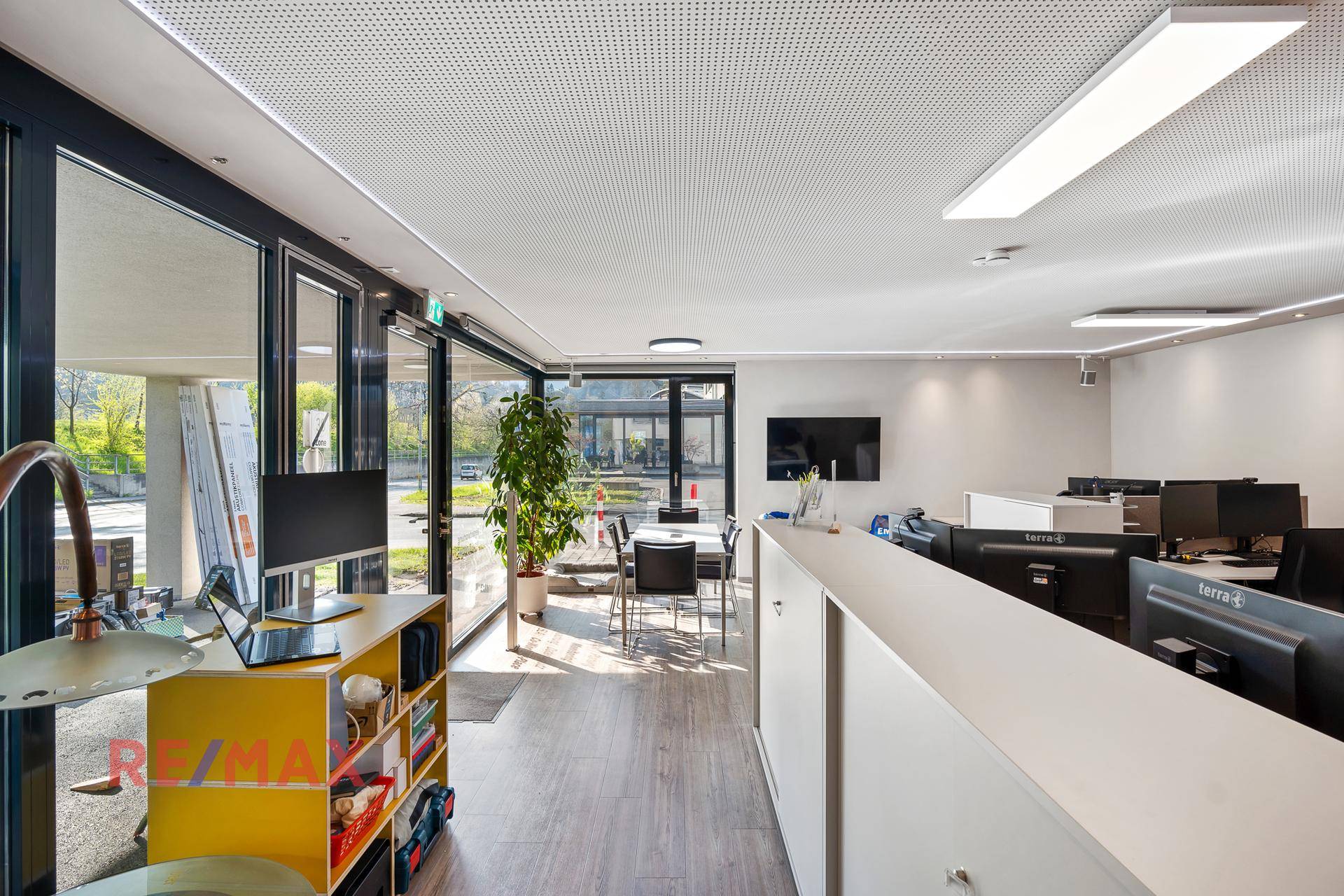 Offenes Büro mit viel Tageslicht durch raumhohe Fenster und einem modernen Besprechungsbereich.
