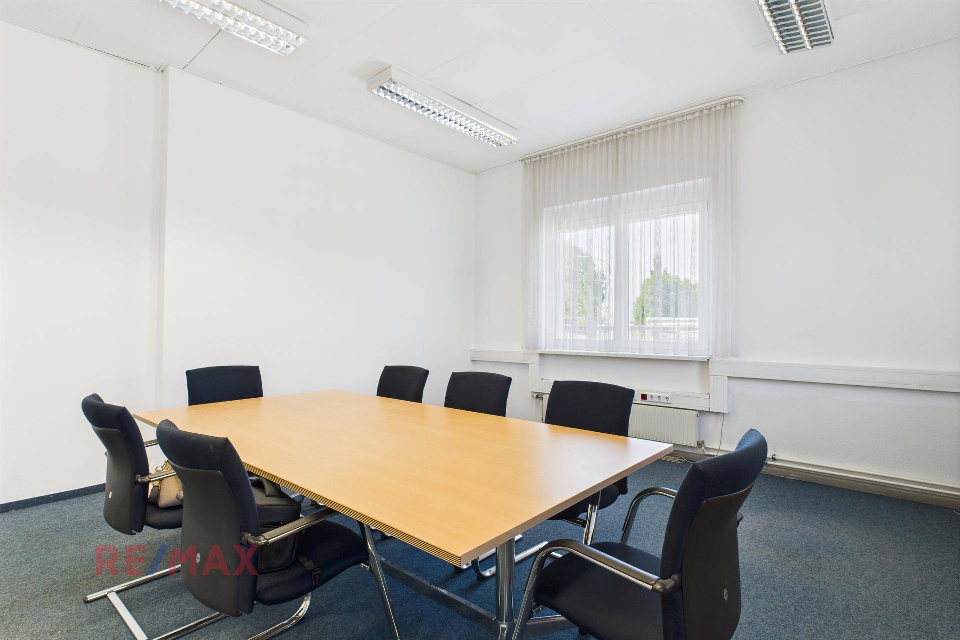 Besprechungsraum mit großem Holztisch und bequemen Bürostühlen, ideal für kleinere Arbeitsgruppen und Diskussionen.
