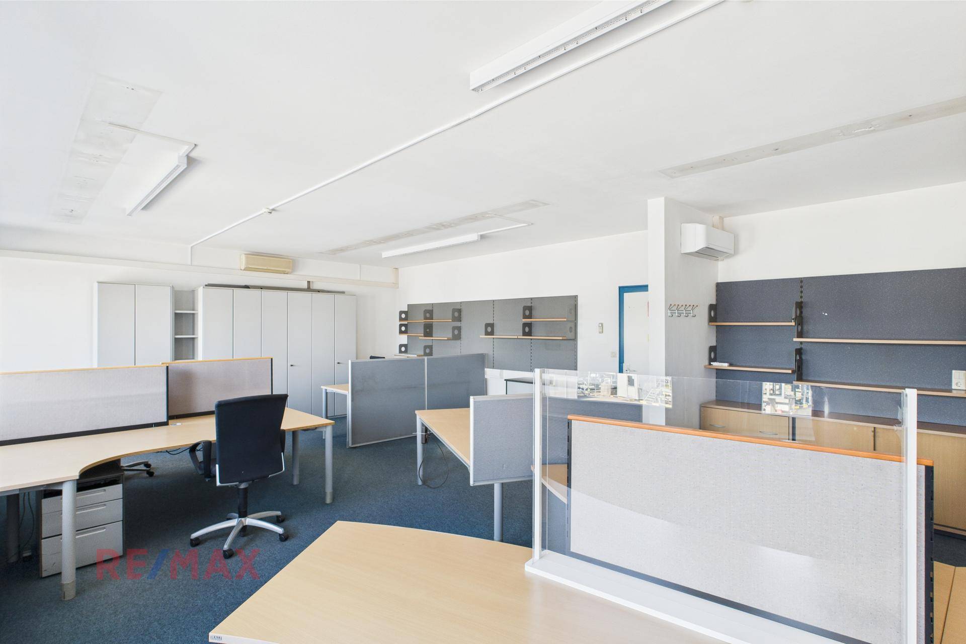 Großraumbüro mit blauem Teppichboden, flexiblen Arbeitsplätzen und Stauraum, ideal für moderne Büroumgebungen.