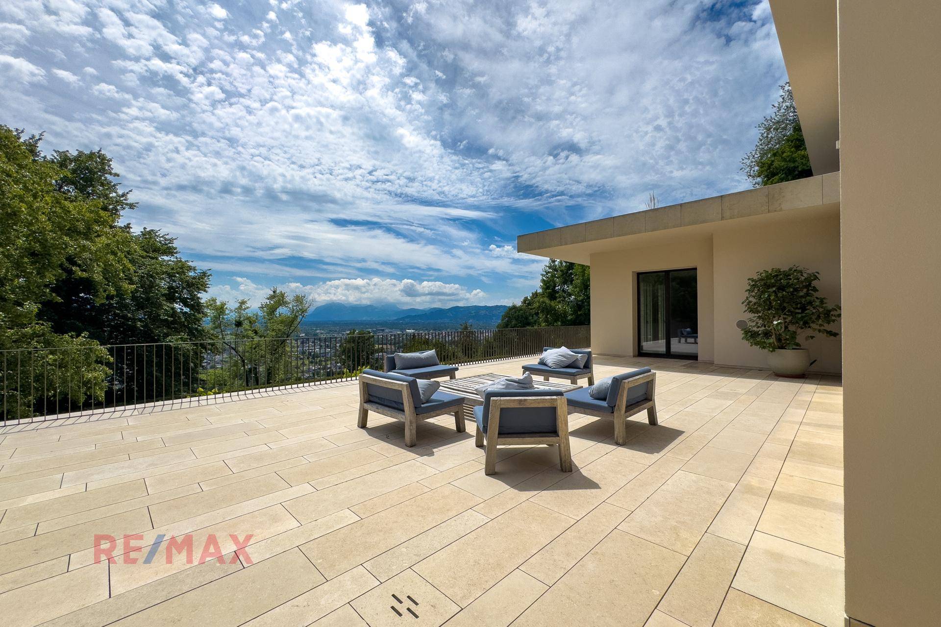 Weitläufige Terrasse mit bequemen Loungemöbeln und Panoramablick auf die Stadt und Berge.