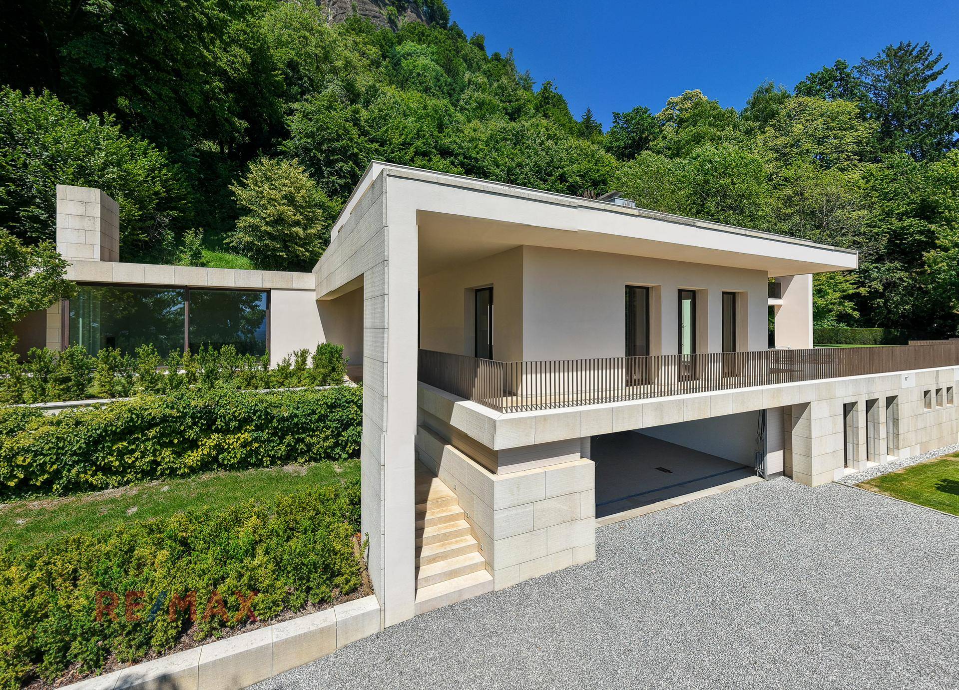 Moderne Architektur des Hauses mit integrierter Garage und Treppenaufgang, umgeben von viel Grün.