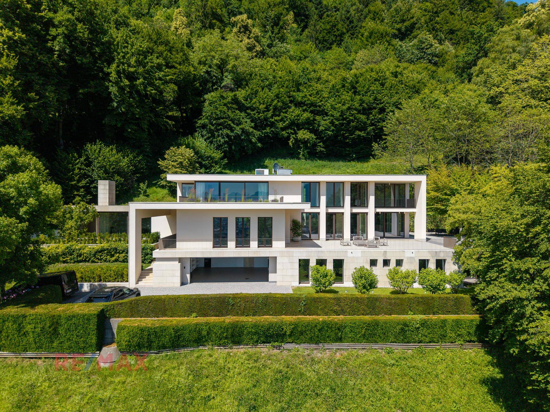 Beeindruckende moderne Villa mit Flachdach und großen Fensterfronten, eingebettet in grüne Natur.