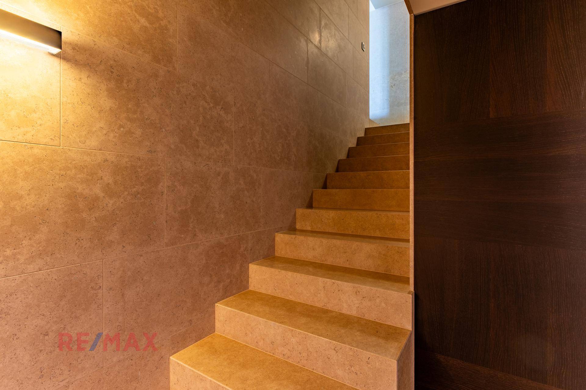 Elegante Treppe mit Steinverkleidung und indirekter Beleuchtung in einem modernen Flur.