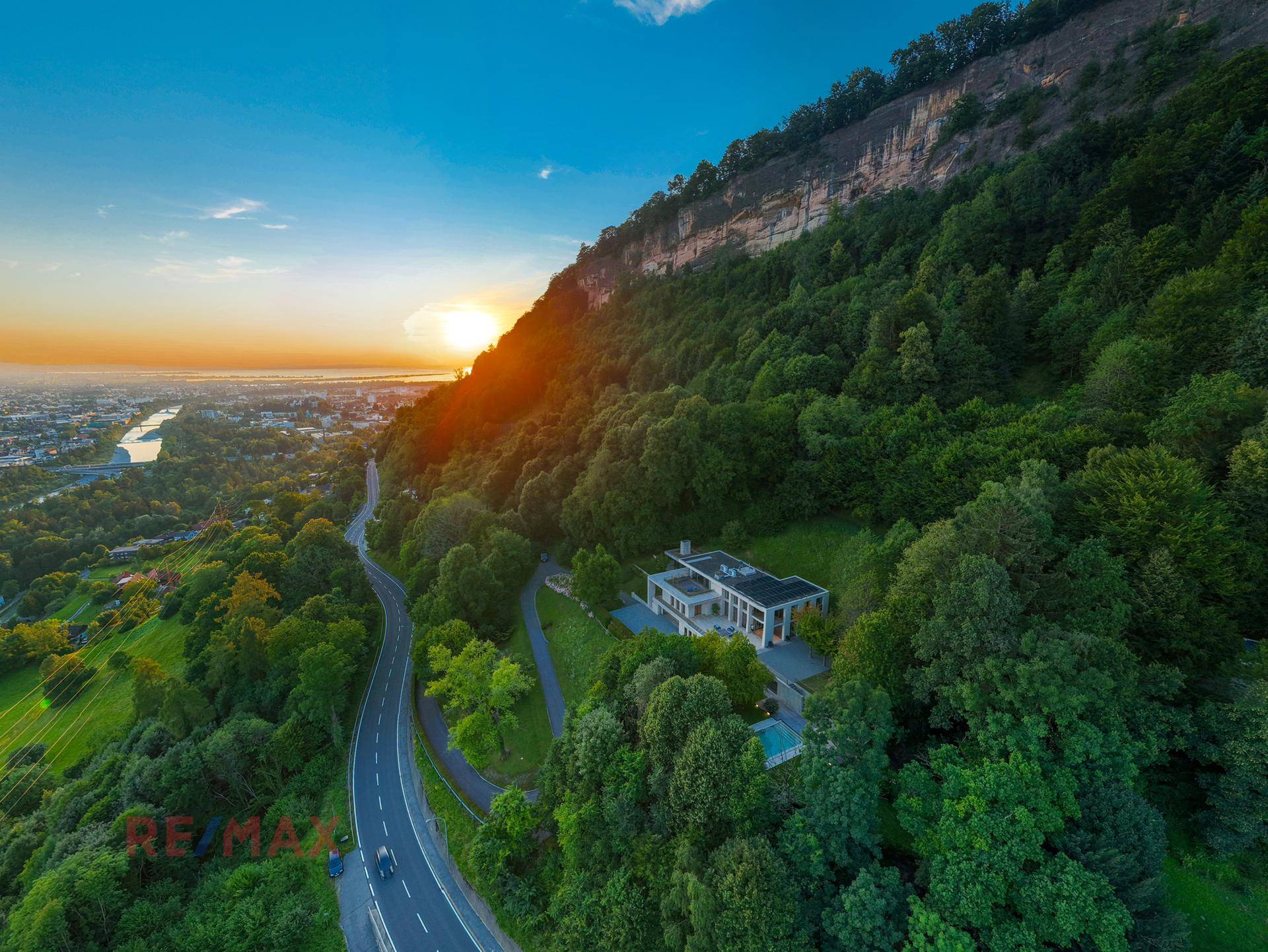 Spektakuläre Luftaufnahme der Villa in Hanglage bei Sonnenuntergang, umgeben von Wald.