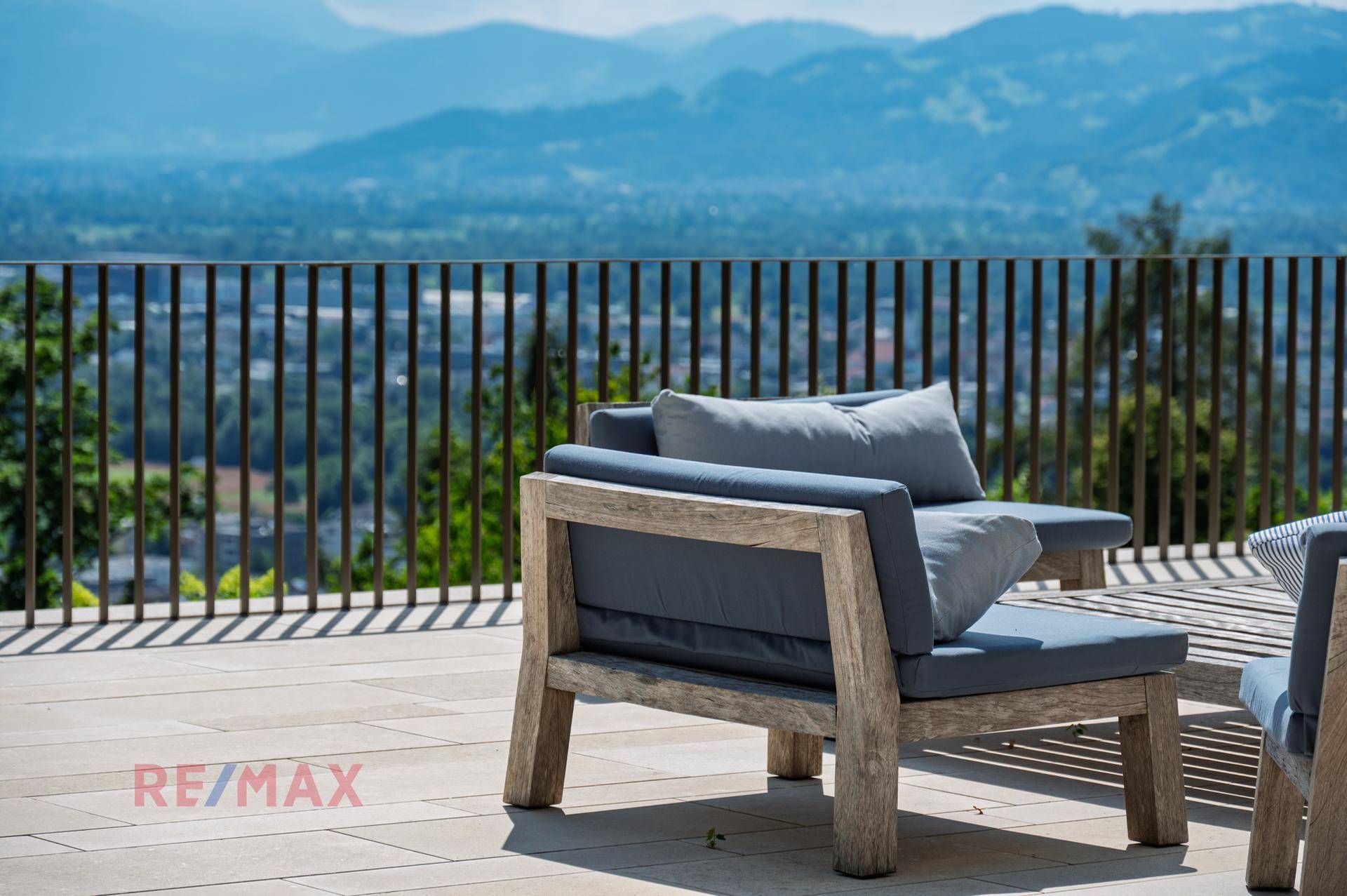 Gemütliche Loungemöbel auf der Terrasse mit weitem Blick über die Landschaft und Berge.