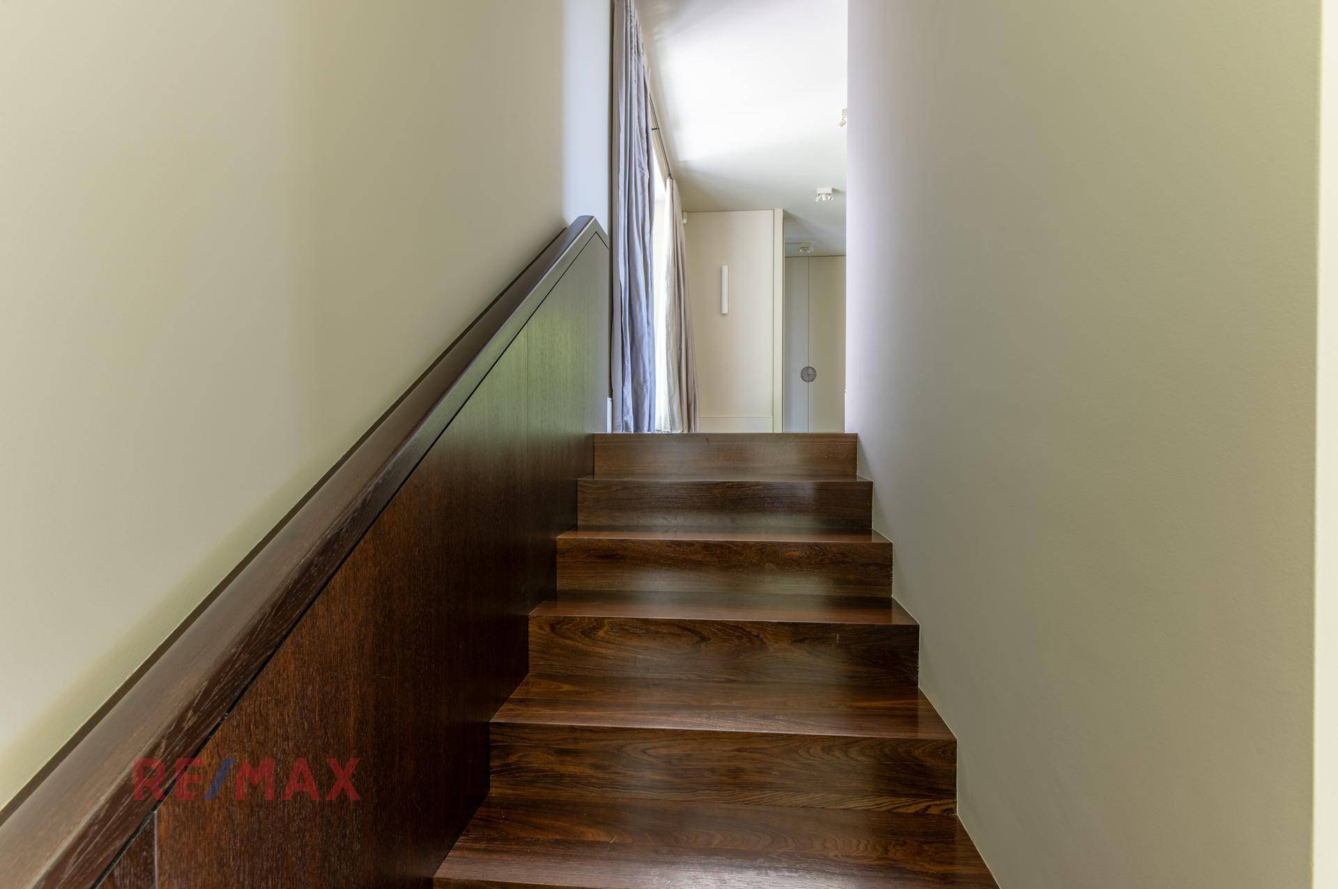 Elegante Holztreppe mit dunklem Geländer führt in die obere Etage.