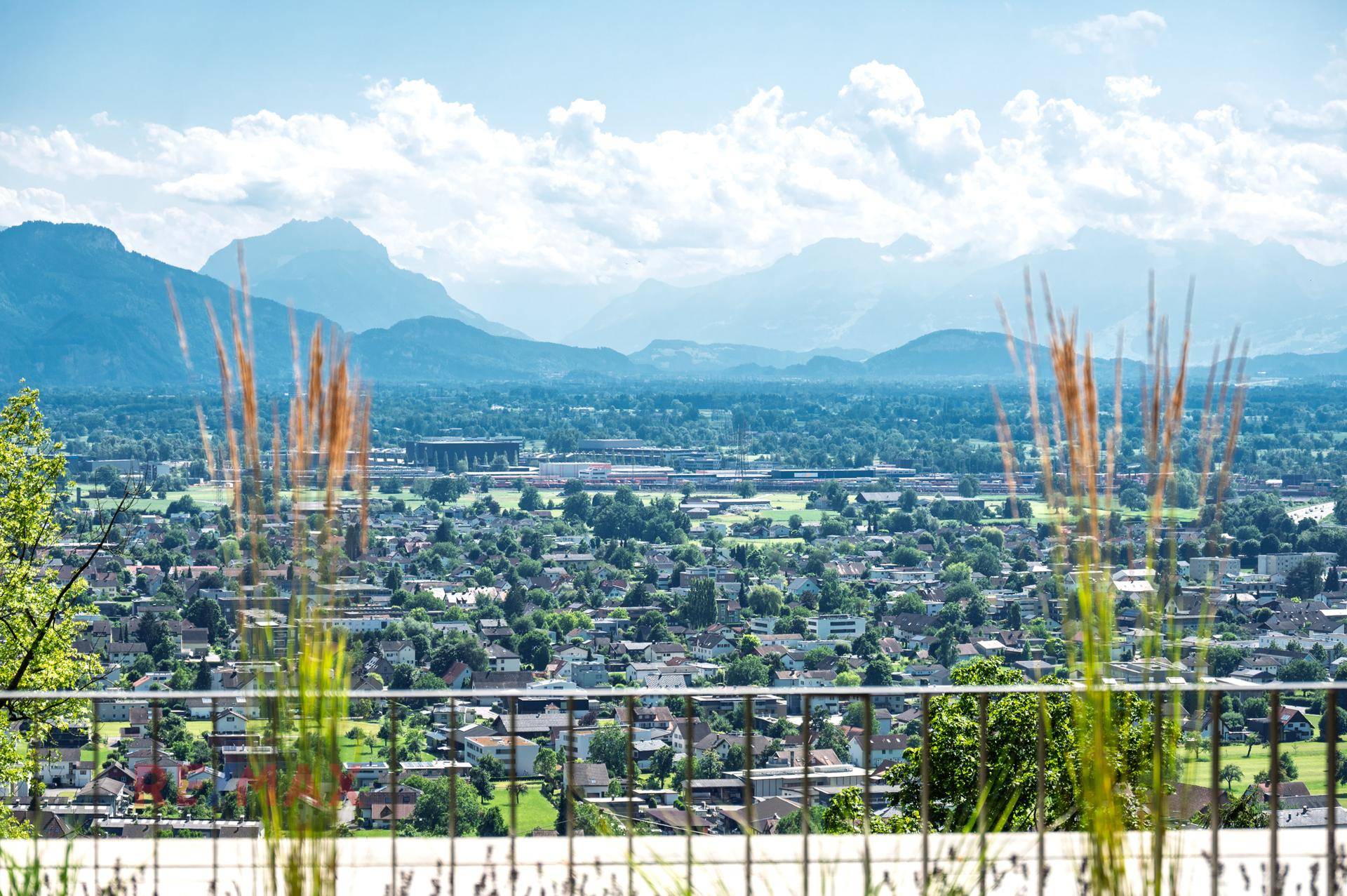 Panoramablick über die weite Landschaft mit Stadt und Bergen im Hintergrund.