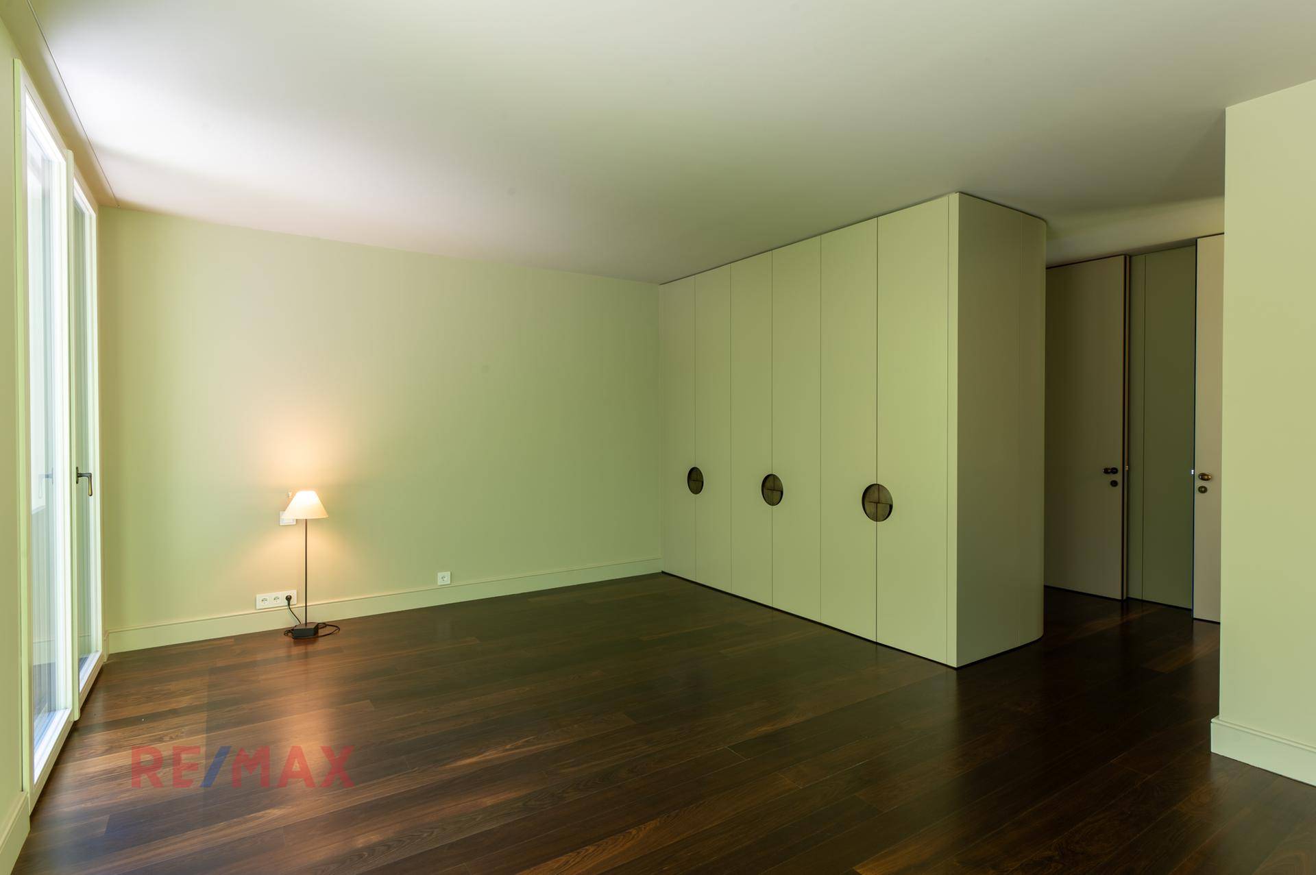 Geräumiges Schlafzimmer mit dunklem Holzboden und praktischen Einbauschränken.