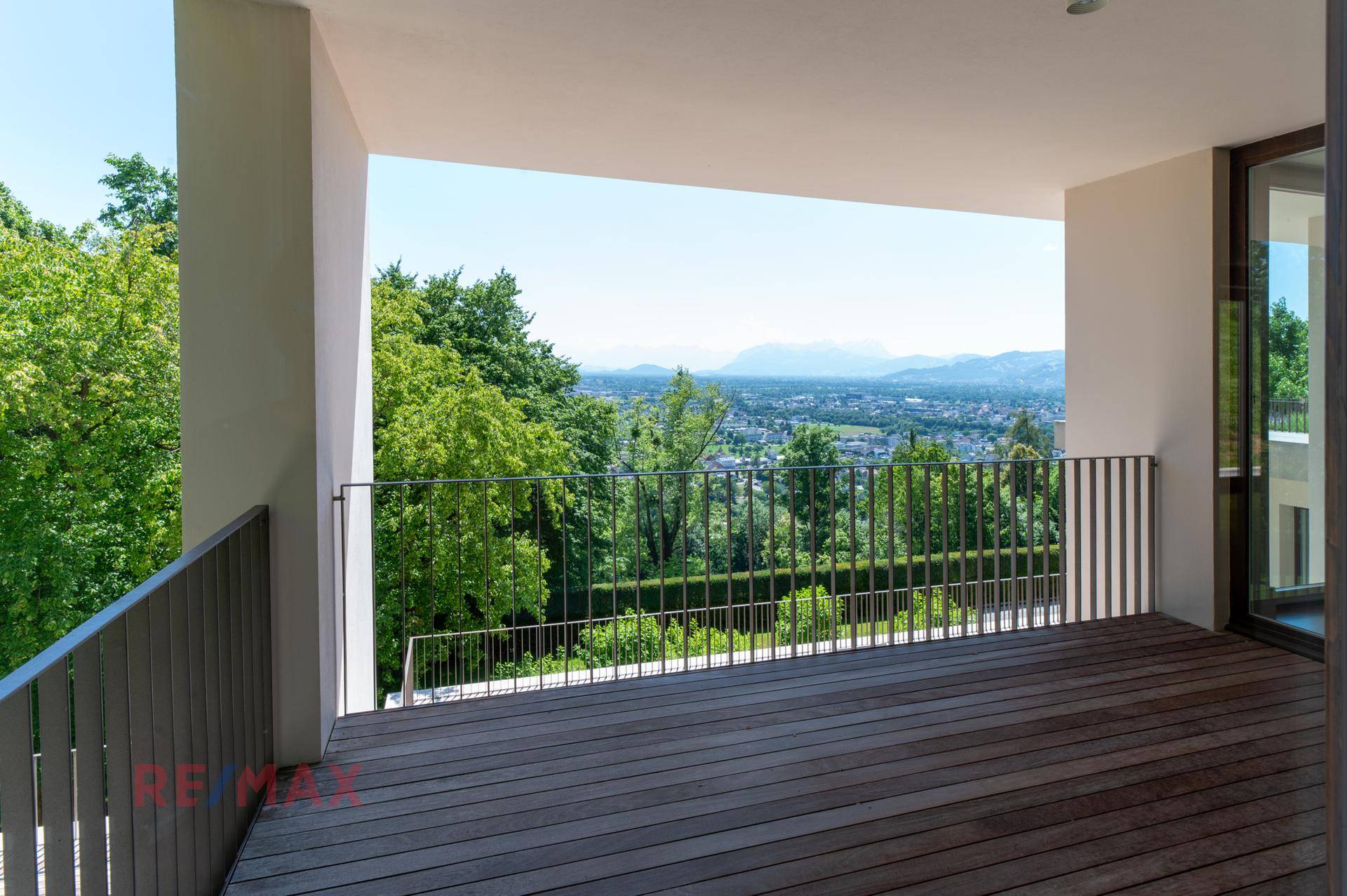 Überdachter Balkon mit weitem Blick über die grüne Landschaft und die Stadt.
