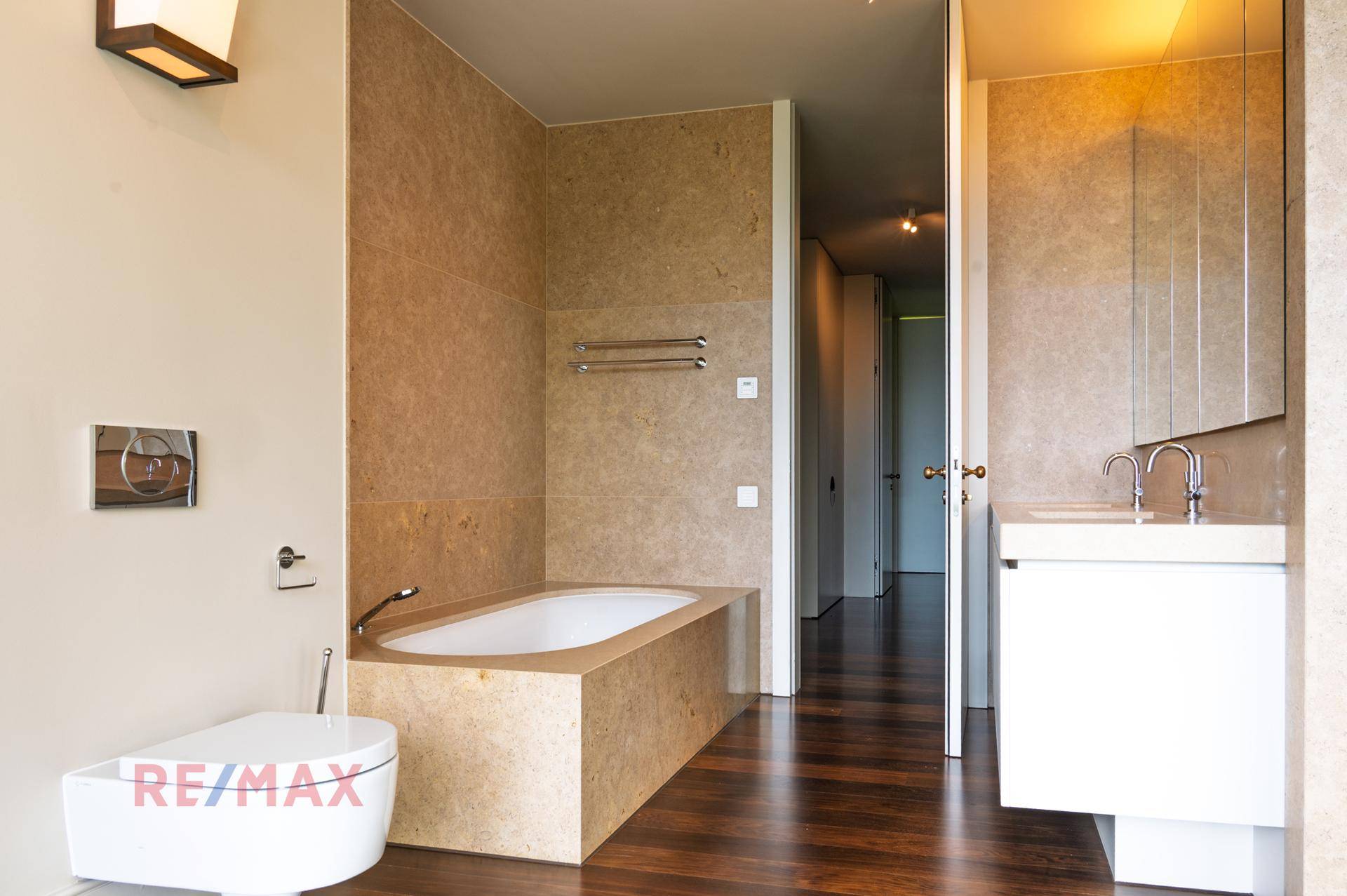Modernes Badezimmer mit Badewanne, Waschtisch und Wand-WC, hell gefliest.
