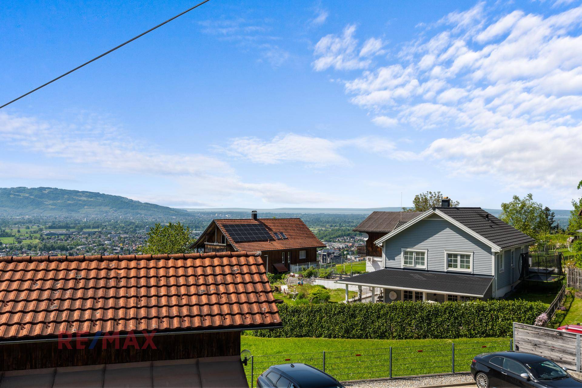Blick auf Wohnhäuser in ländlicher Umgebung mit einem grauen Haus und roten Ziegeldächern.