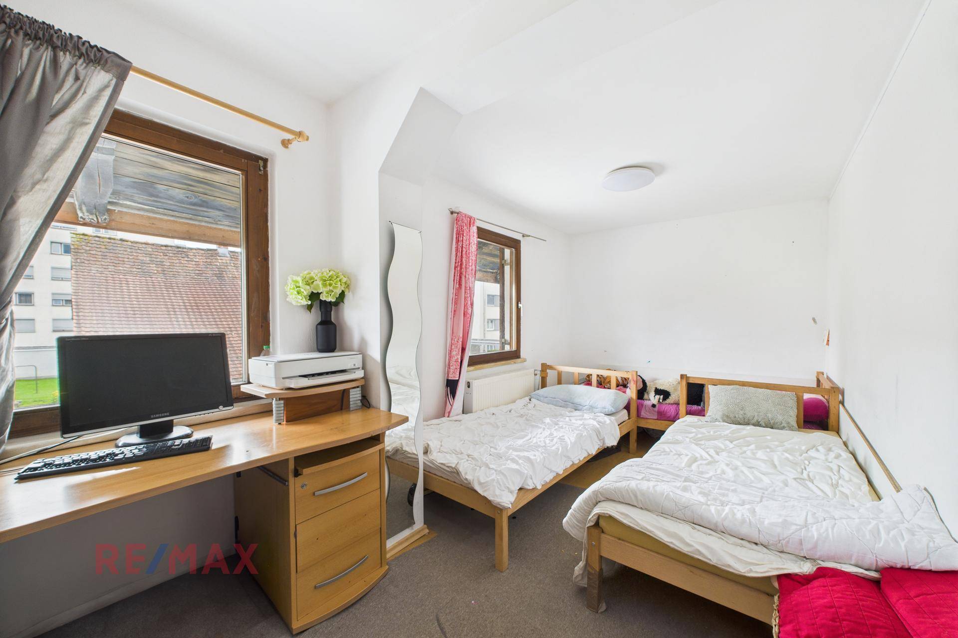 Schlafzimmer mit zwei Einzelbetten, Schreibtisch und Fenster für Tageslicht.