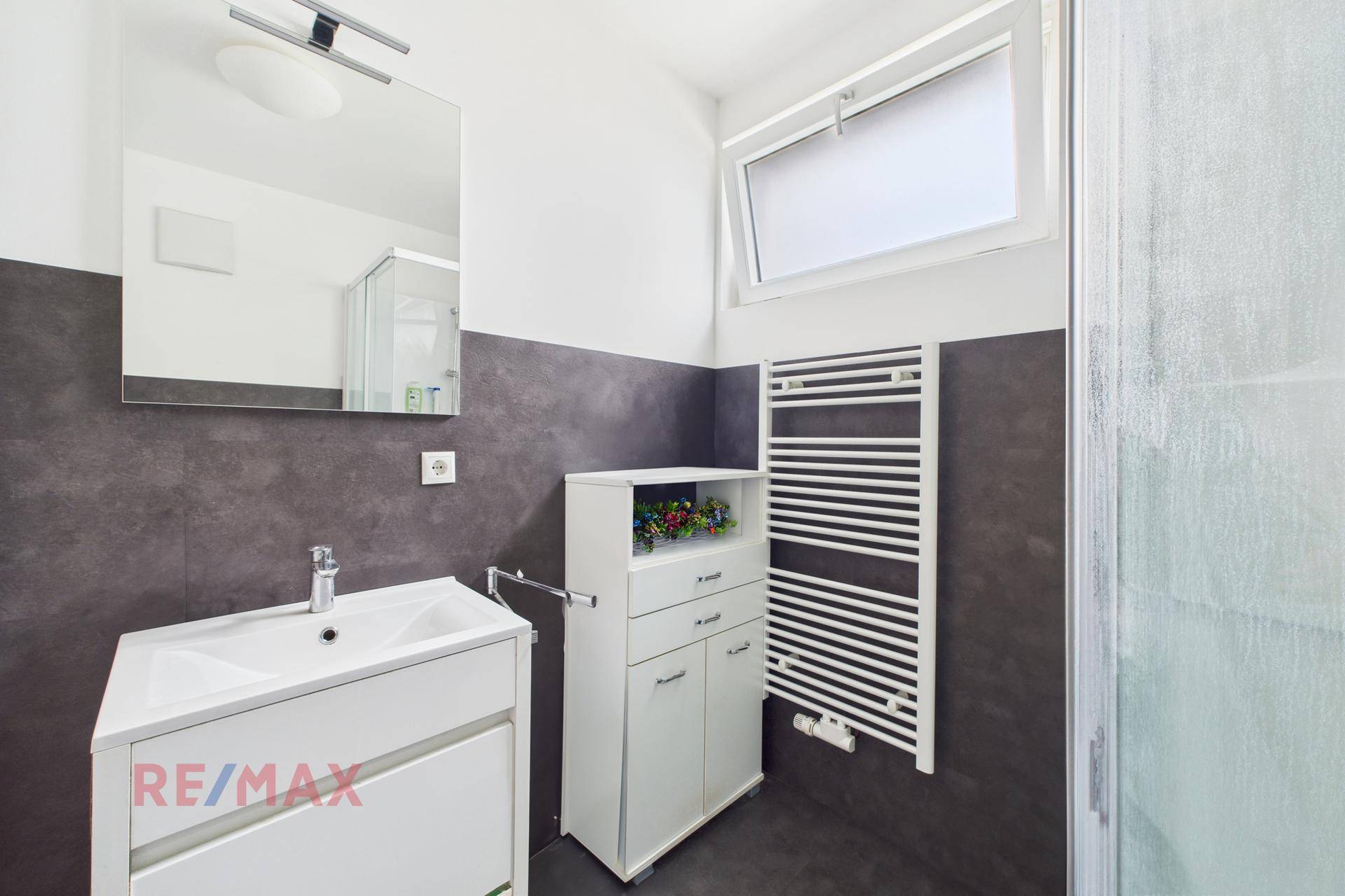 Helles Badezimmer mit Waschbecken, Spiegelschrank und Fenster für Tageslicht.