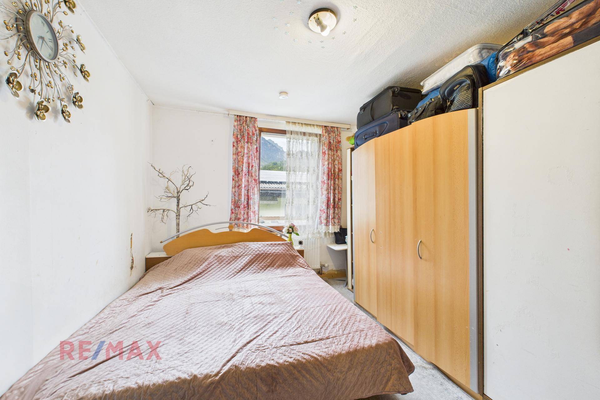 Schlafzimmer mit Einzelbett, Kleiderschrank und Fenster mit Blick ins Grüne.