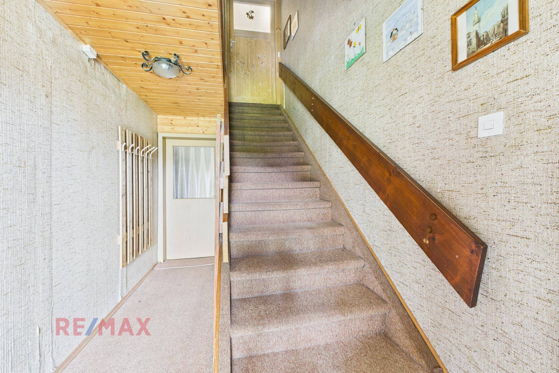Eingangsbereich mit Teppichboden auf der Treppe und Holzverkleidung an der Decke.
