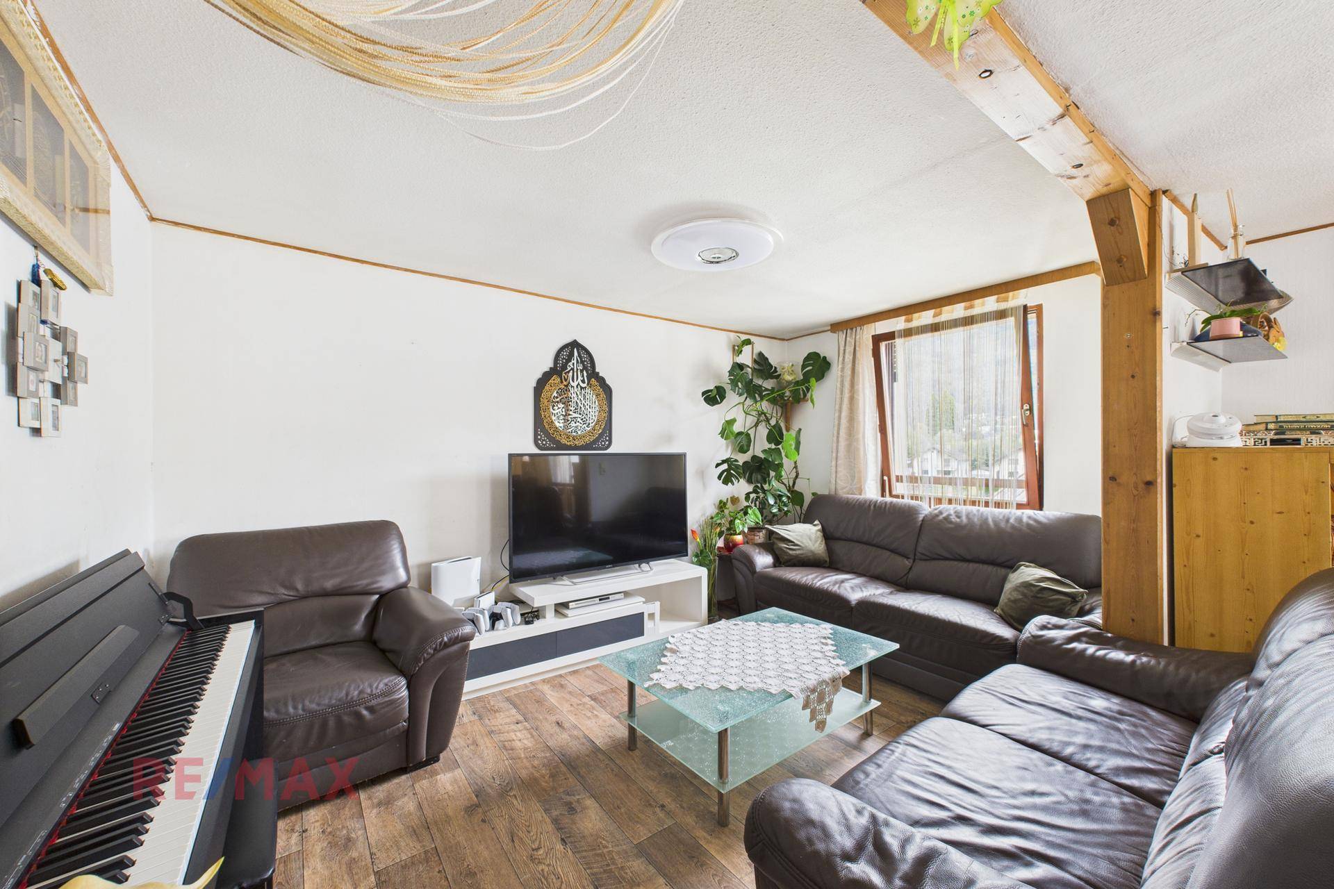 Gemütliches Wohnzimmer mit Ledersofas, Fernseher und Klavier, ideal für entspannte Abende.