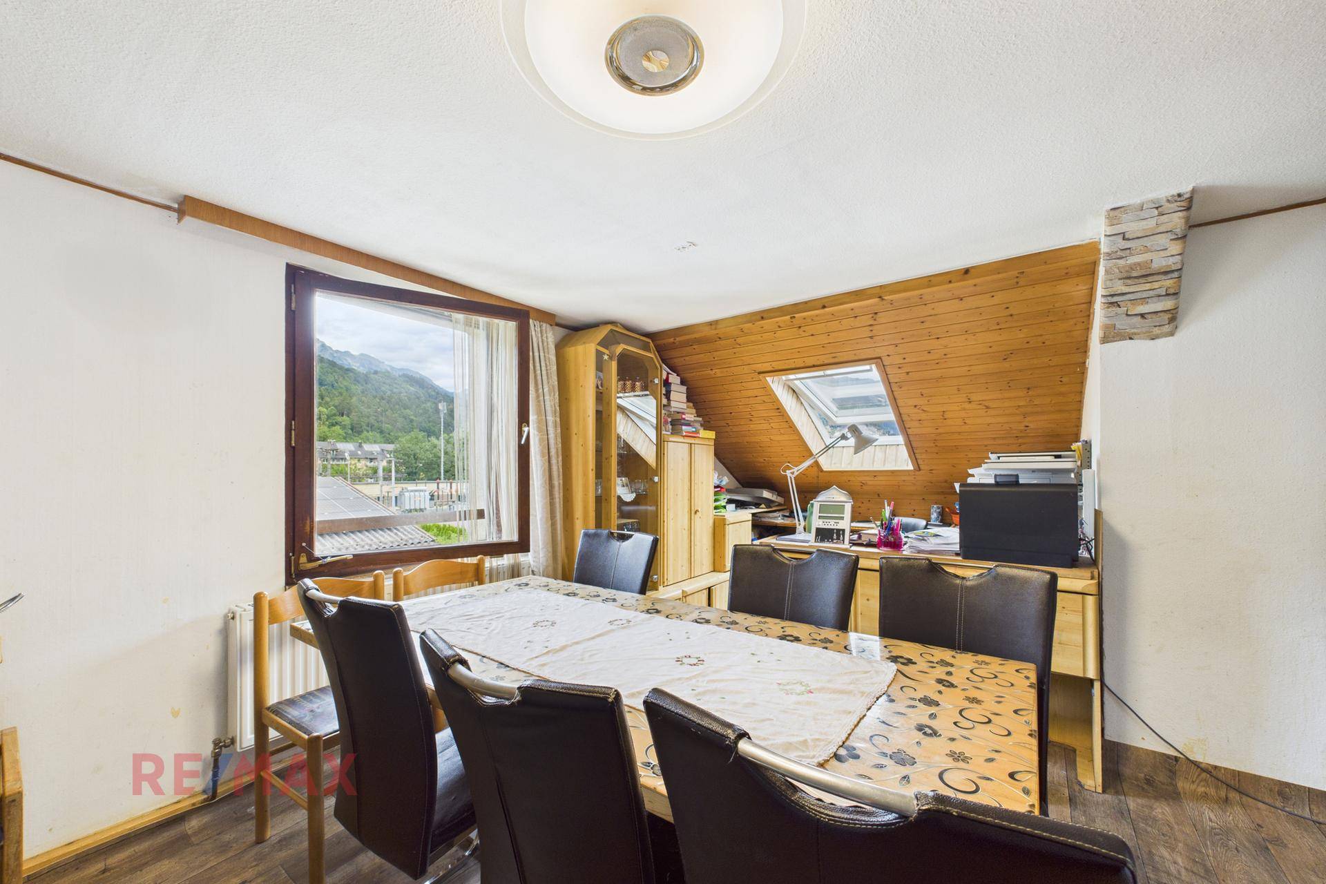 Esszimmer mit großem Tisch, Stühlen und Dachschrägenfenster, auch als Arbeitsbereich nutzbar.