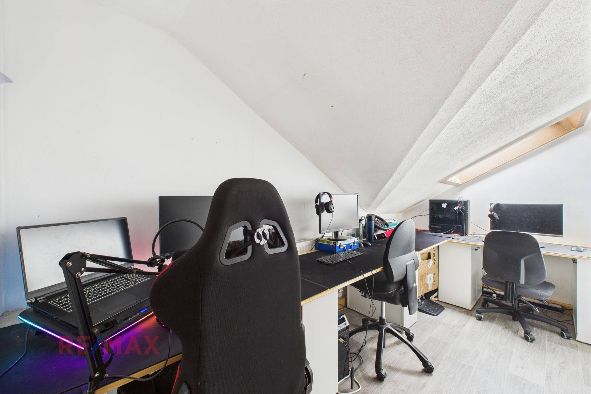 Geräumiges Büro mit mehreren Arbeitsplätzen, Gaming-Stühlen und Dachschrägenfenstern.