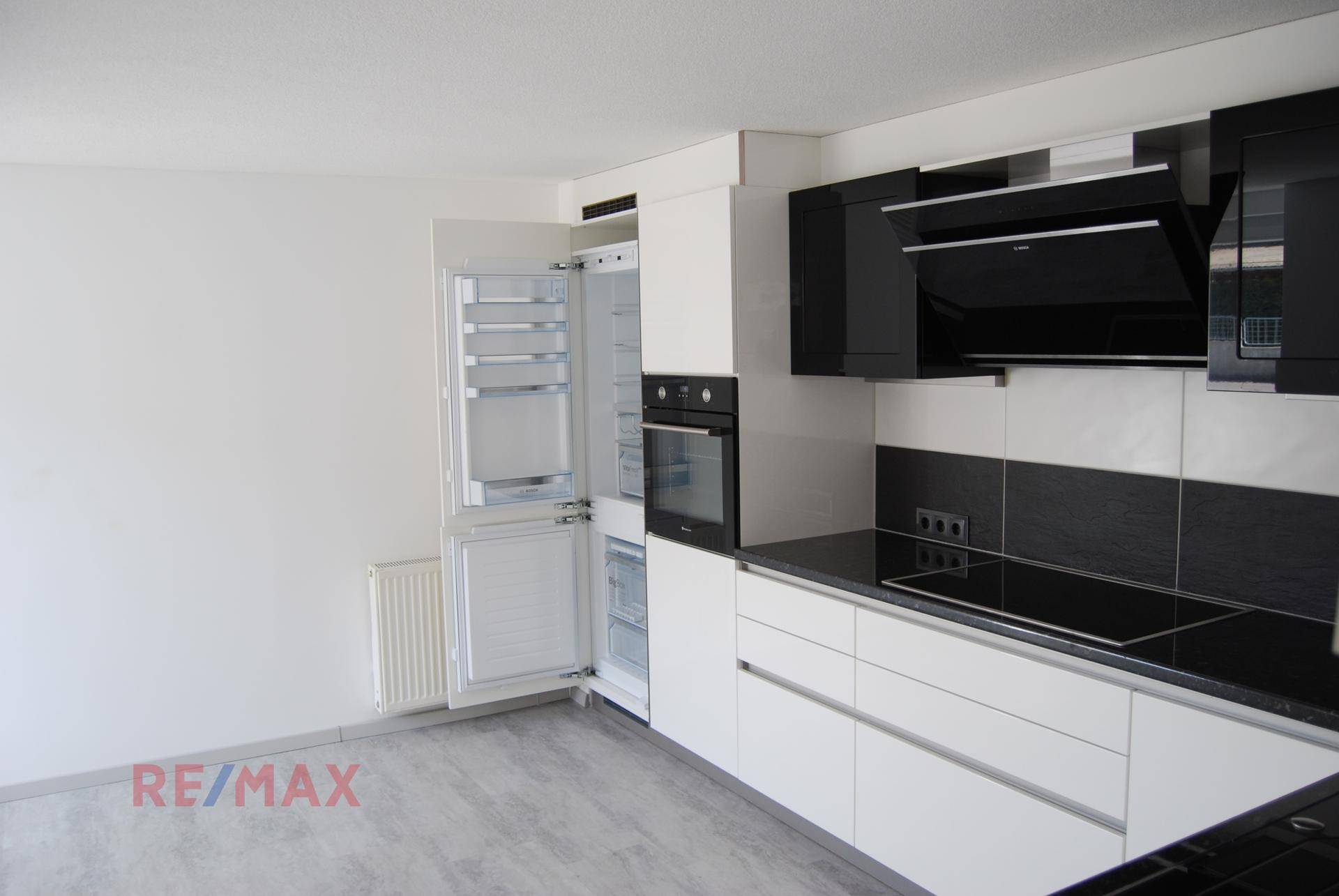 Moderne Küchenzeile in Schwarz-Weiß mit integrierten Geräten, Kochfeld und Kühlschrank.