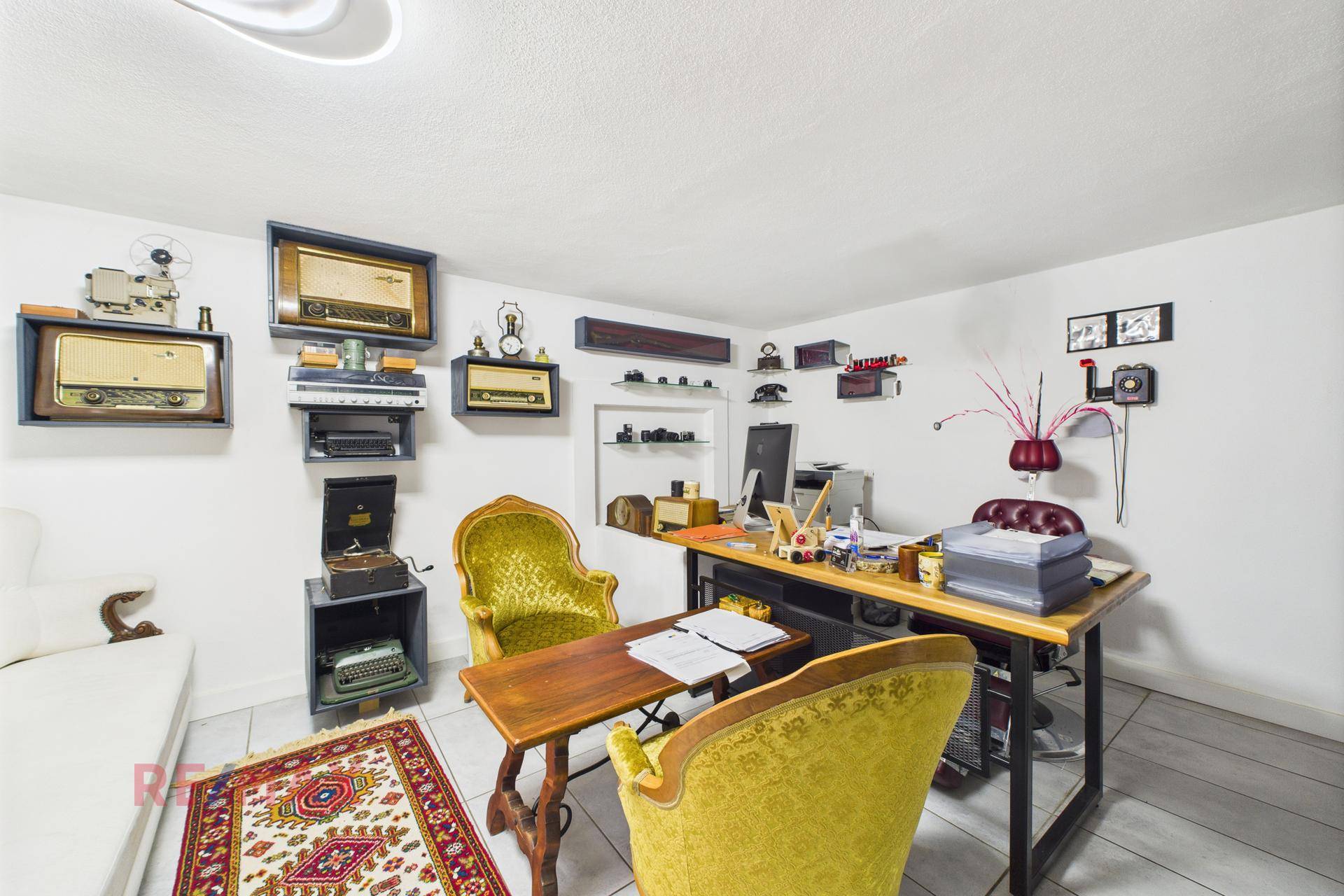 Büro oder Arbeitszimmer mit Vintage-Möbeln und dekorativen Radio-Exponaten an der Wand.