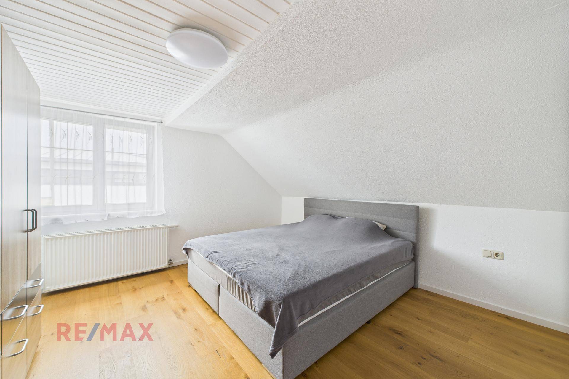 Helles Schlafzimmer im Dachgeschoss mit Doppelbett und Holzboden.