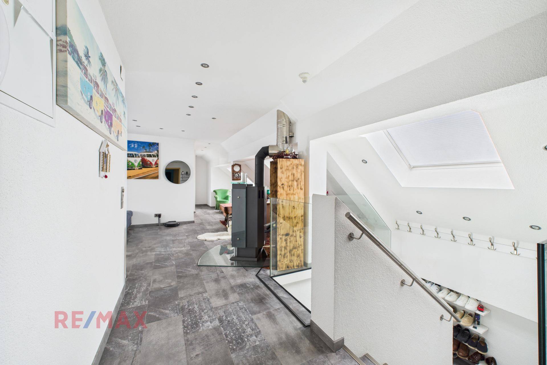 Heller Flur im Dachgeschoss mit Kaminofen, Treppe und Schuhregal.