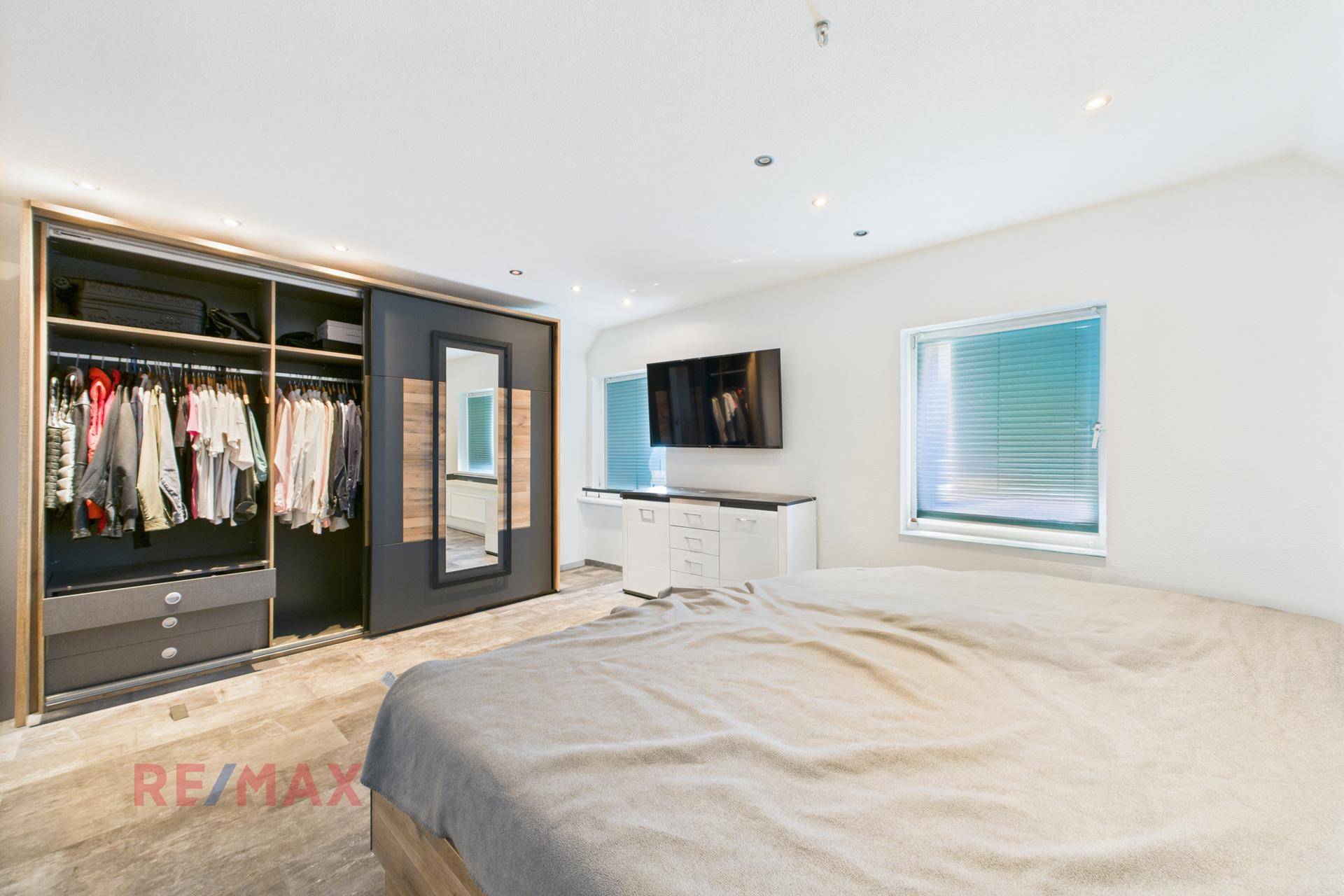 Geräumiges Schlafzimmer mit Doppelbett, Einbauschrank und großen Fenstern.