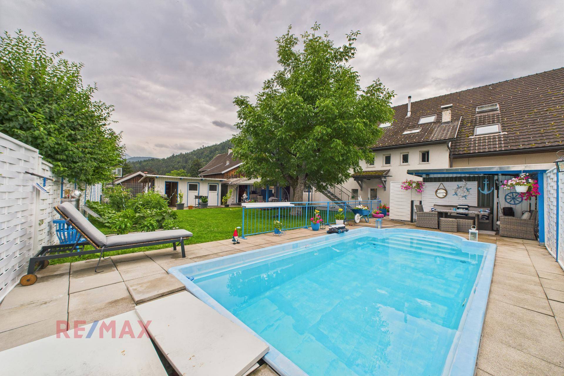 Großer Garten mit Swimmingpool, Liegestühlen und überdachtem Sitzbereich.