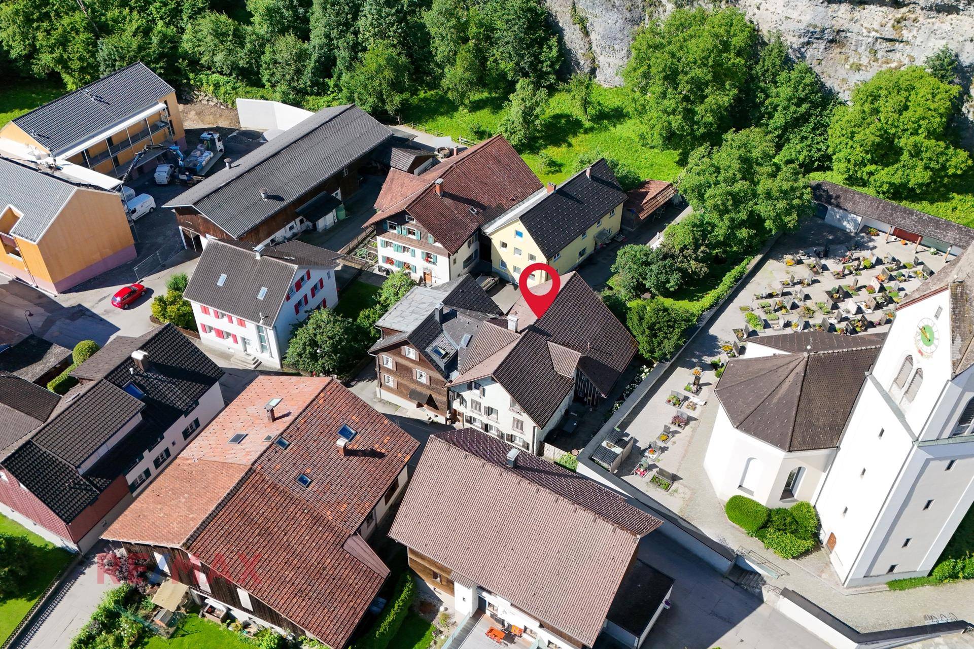 Luftaufnahme des Anwesens mit umliegenden Gebäuden und der Kirche in ländlicher Umgebung.