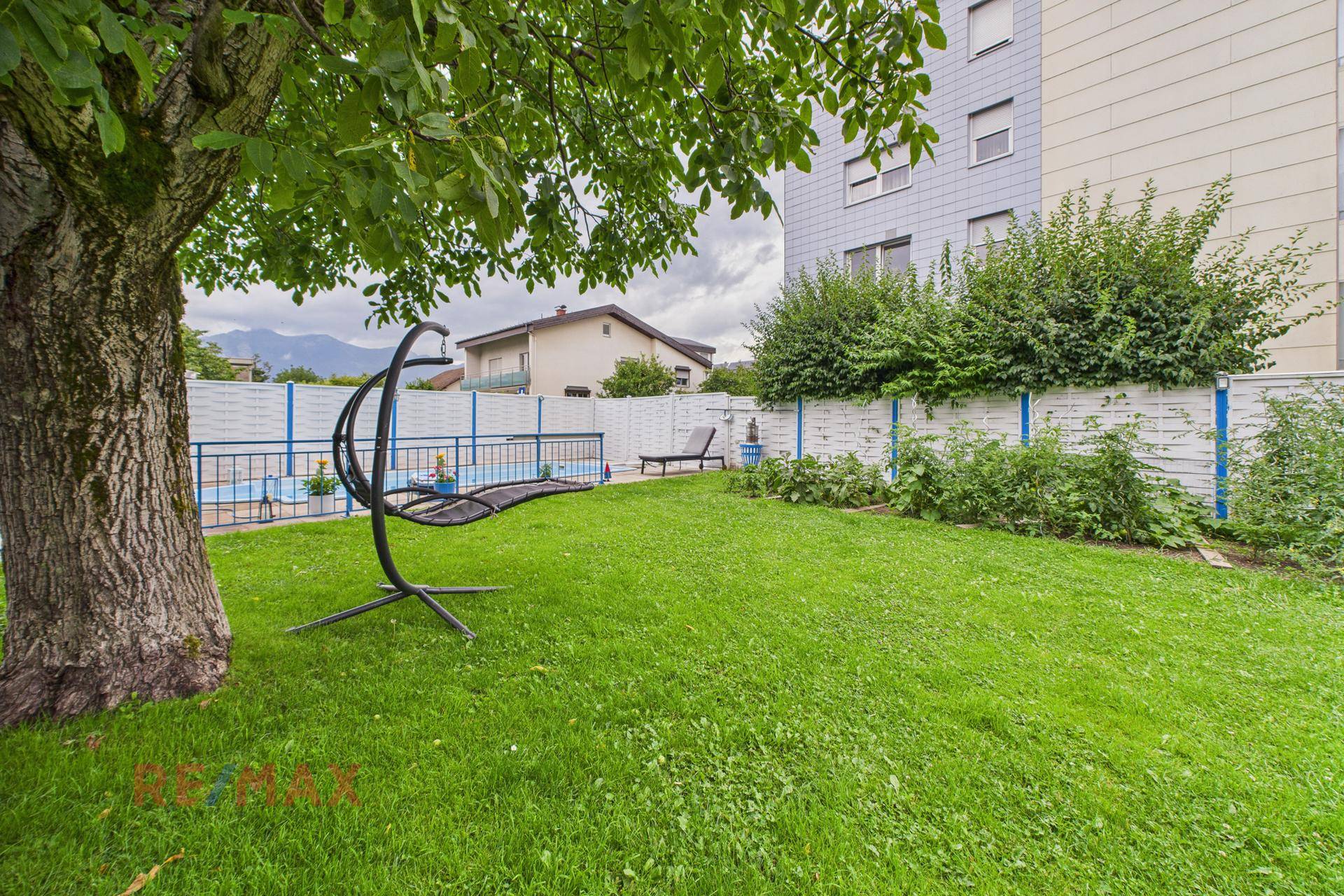 Gepflegter Rasenbereich im Garten mit Schaukelstuhl und grünen Büschen.