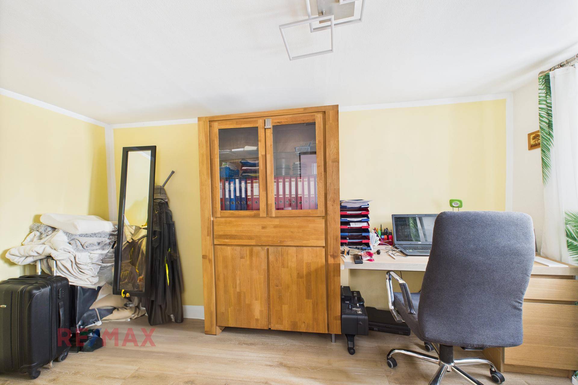 Arbeitszimmer mit Holzschrank, Schreibtisch und hellem Laminatboden.