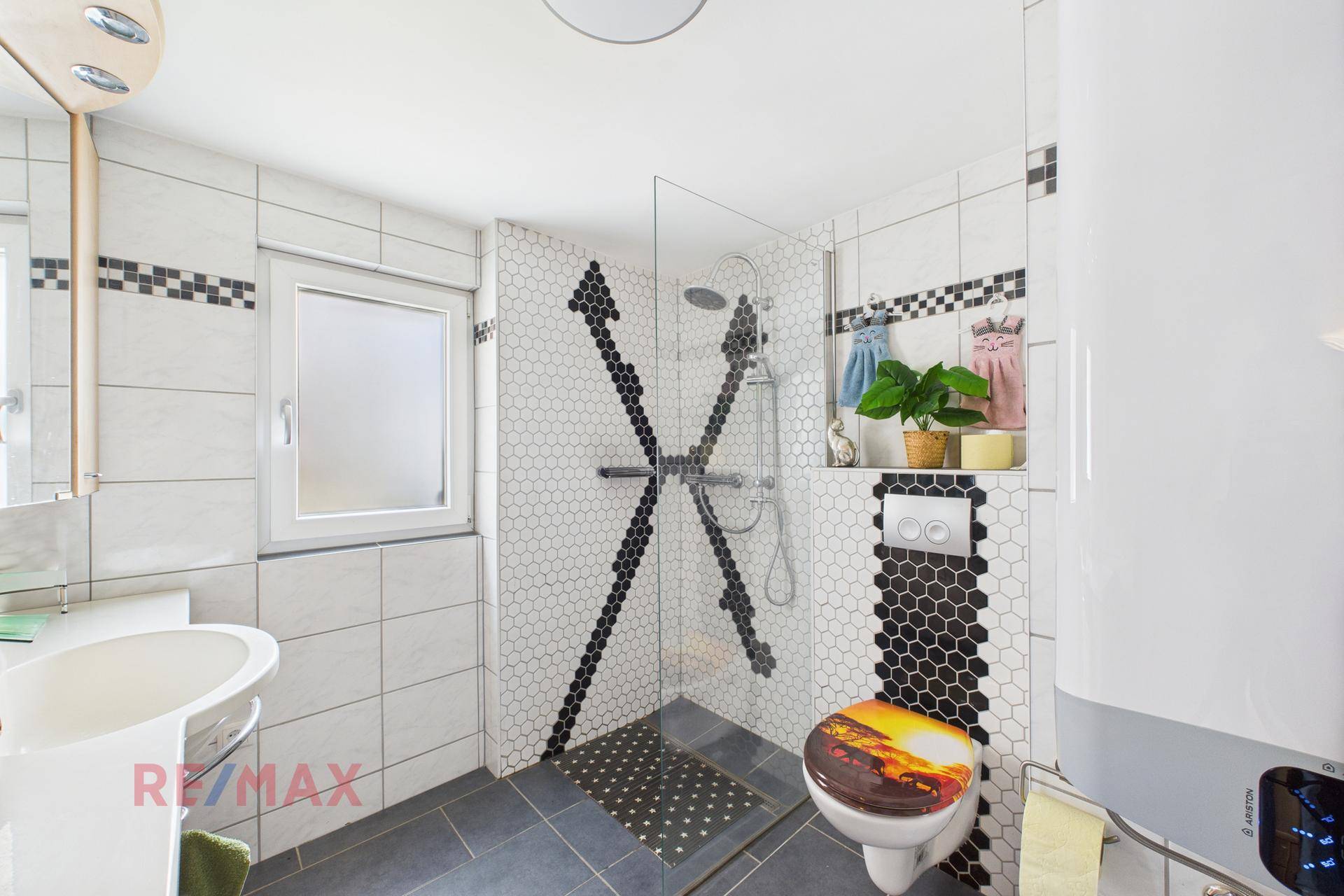 Modernes Badezimmer mit Duschkabine, WC und dekorativen Fliesen.