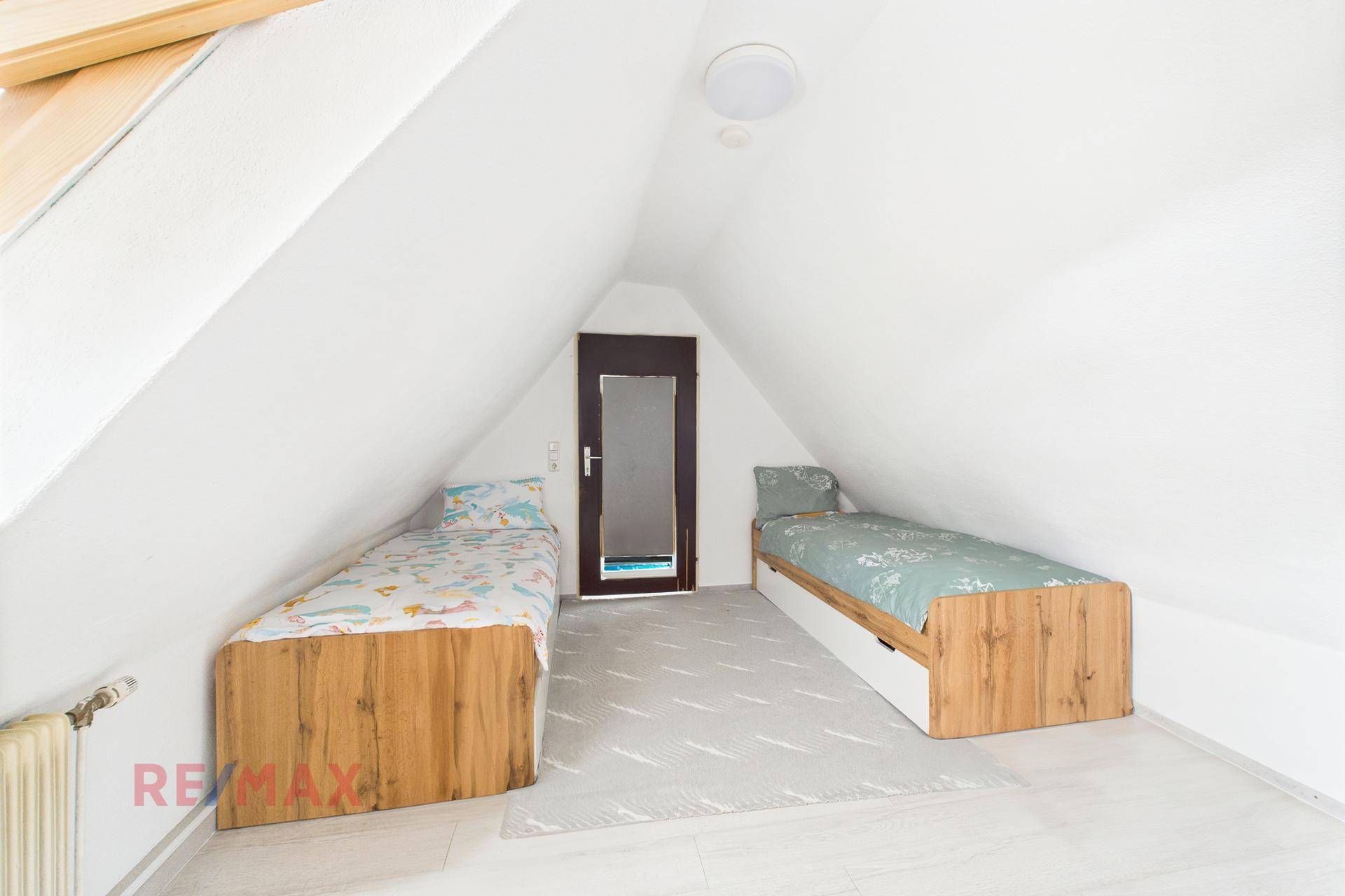 Kinderzimmer unter Dachschräge mit zwei Einzelbetten und Dachfenster.