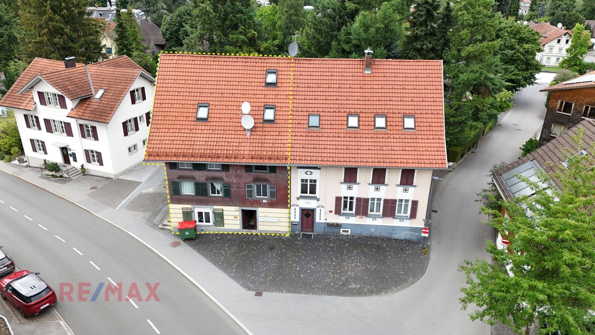 Luftaufnahme eines Mehrfamilienhauses mit Satteldach und umliegender Bebauung.